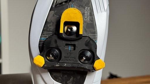 Close-up of a Shimano road cycling shoe sole with a yellow SPD-SLR cleat and black mounting hardware
