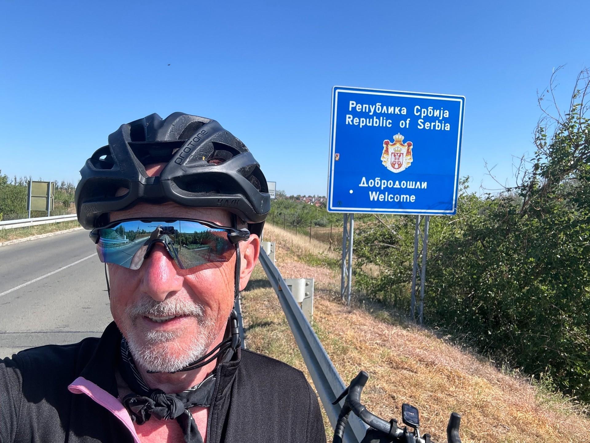 Ewan Kirk in cycling gear beside his loaded gravel bike at the Serbia border crossing.