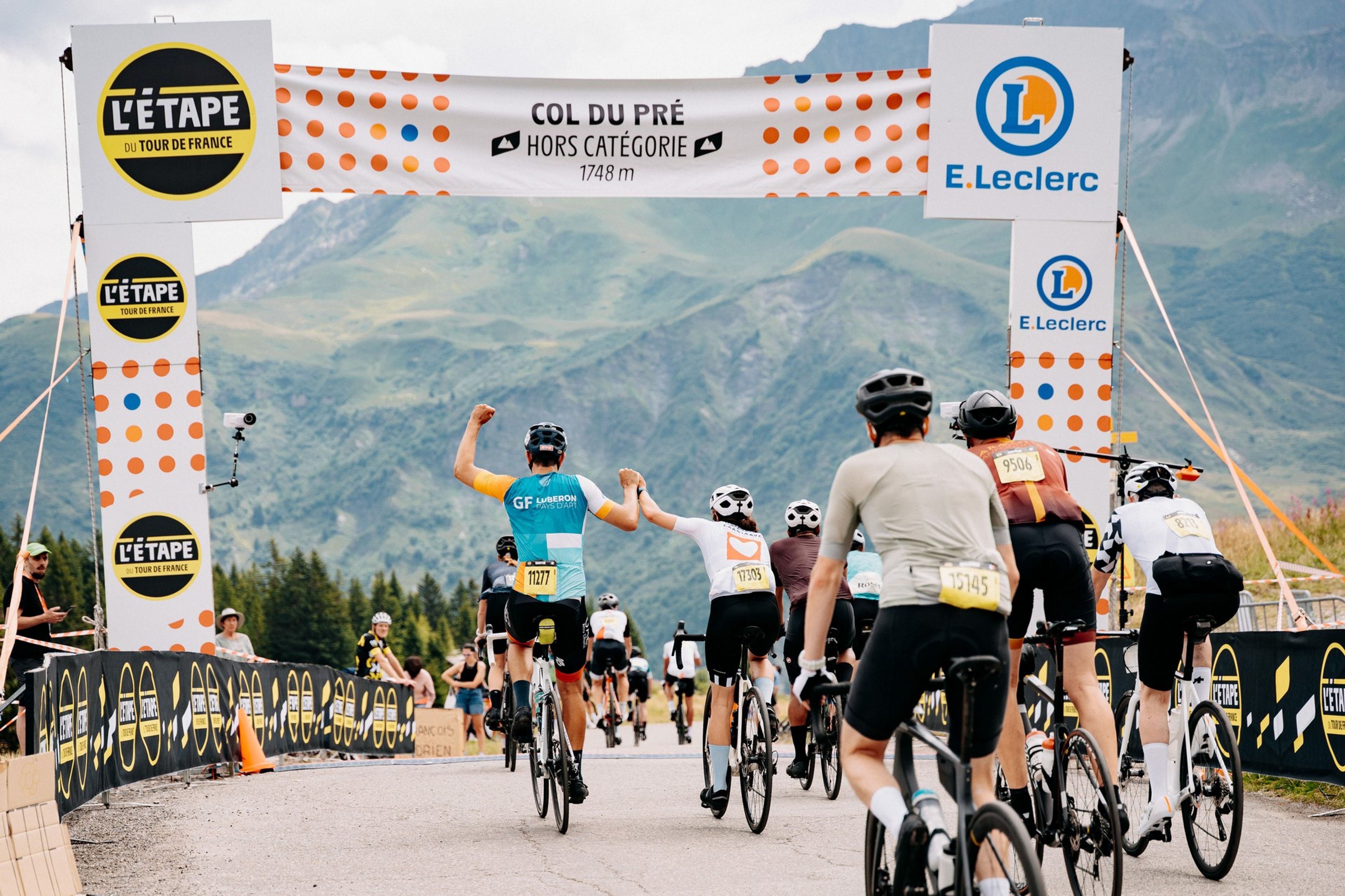 Riders summit Col du Pré banner triumphantly in French Alps sportive