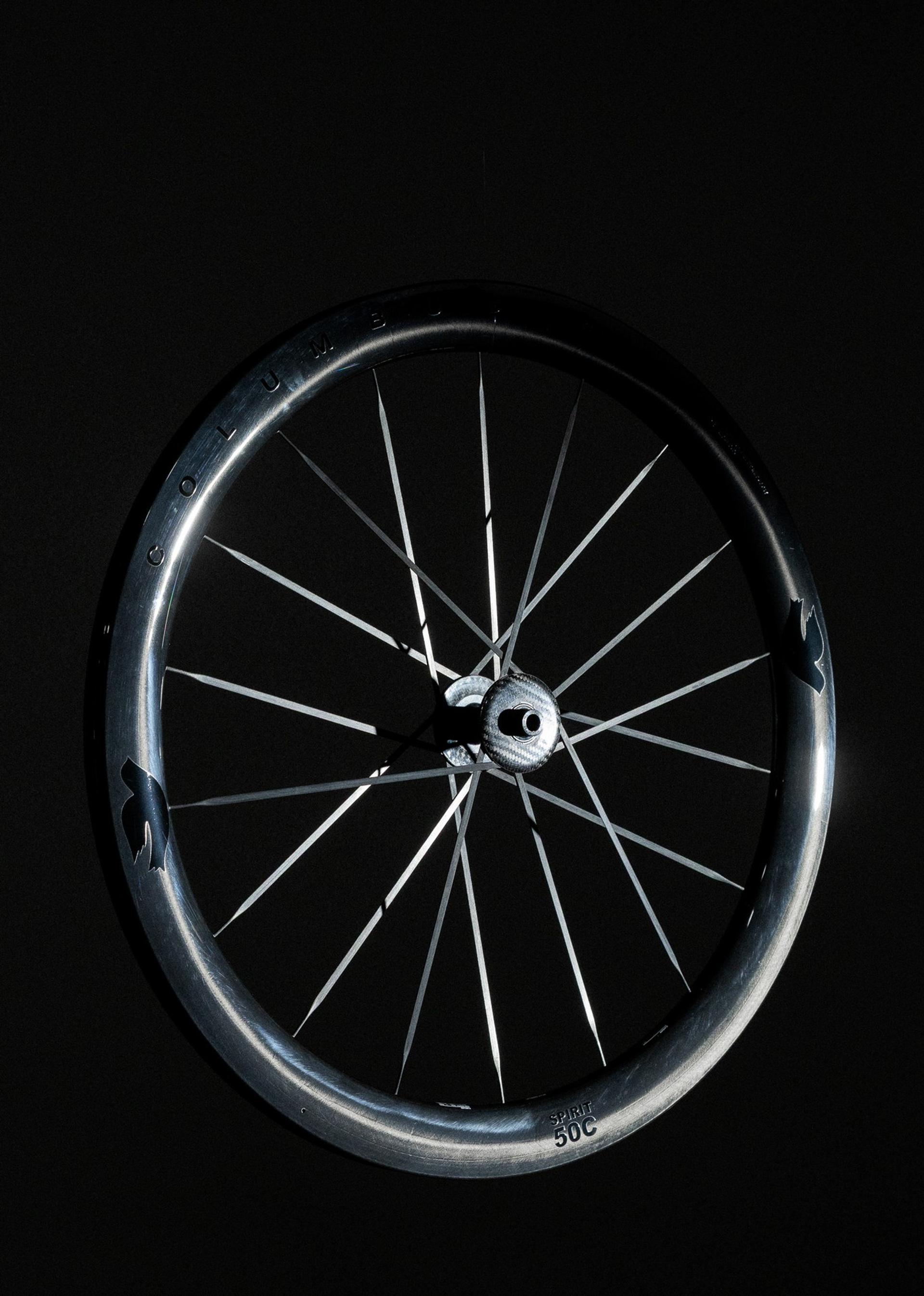 Deep-section carbon road bike wheel with thin spokes and a central hub against a black background