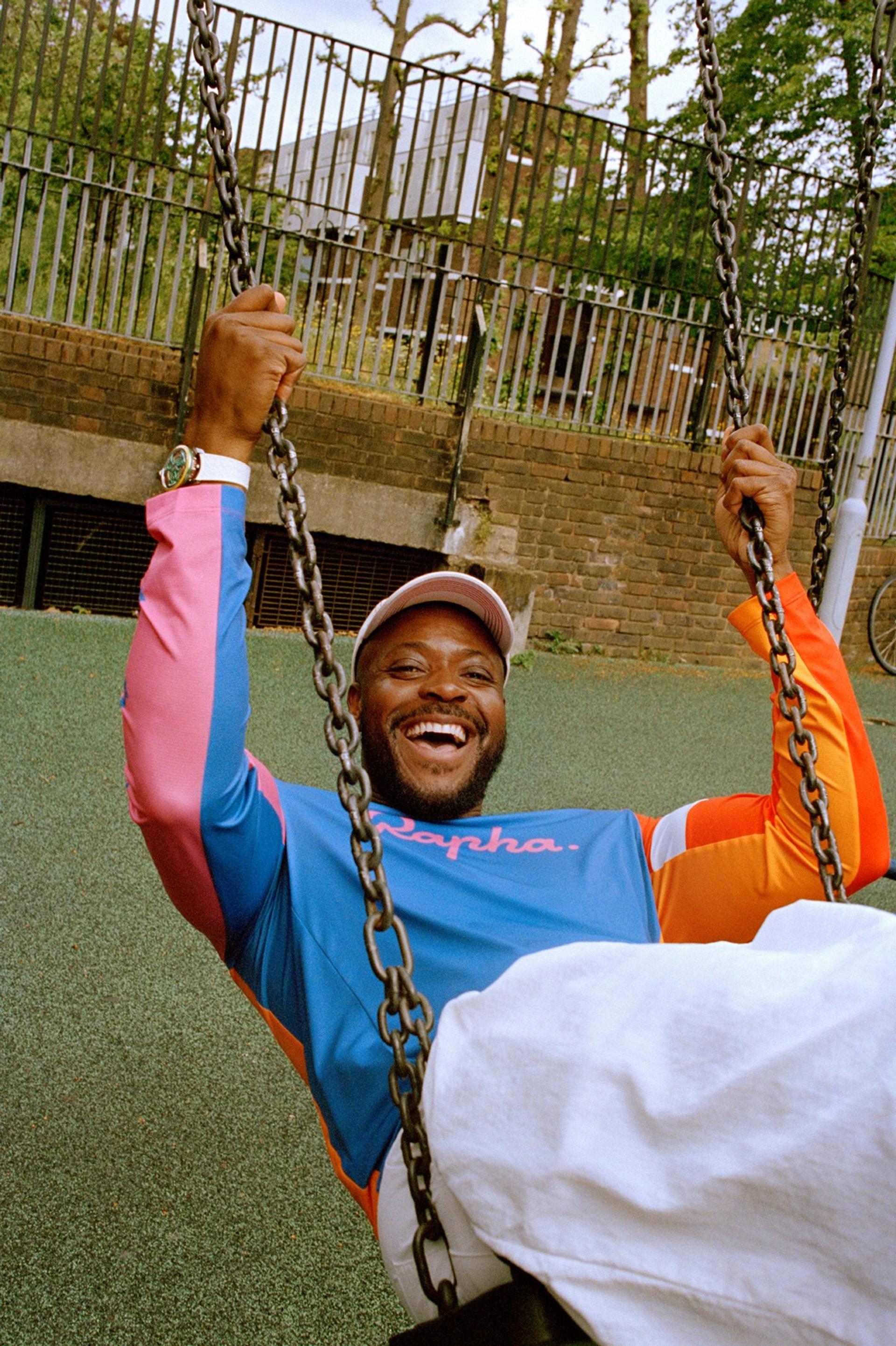 Cyclist in blue-white kit swings on chains during an outdoor training drill in a fenced yard