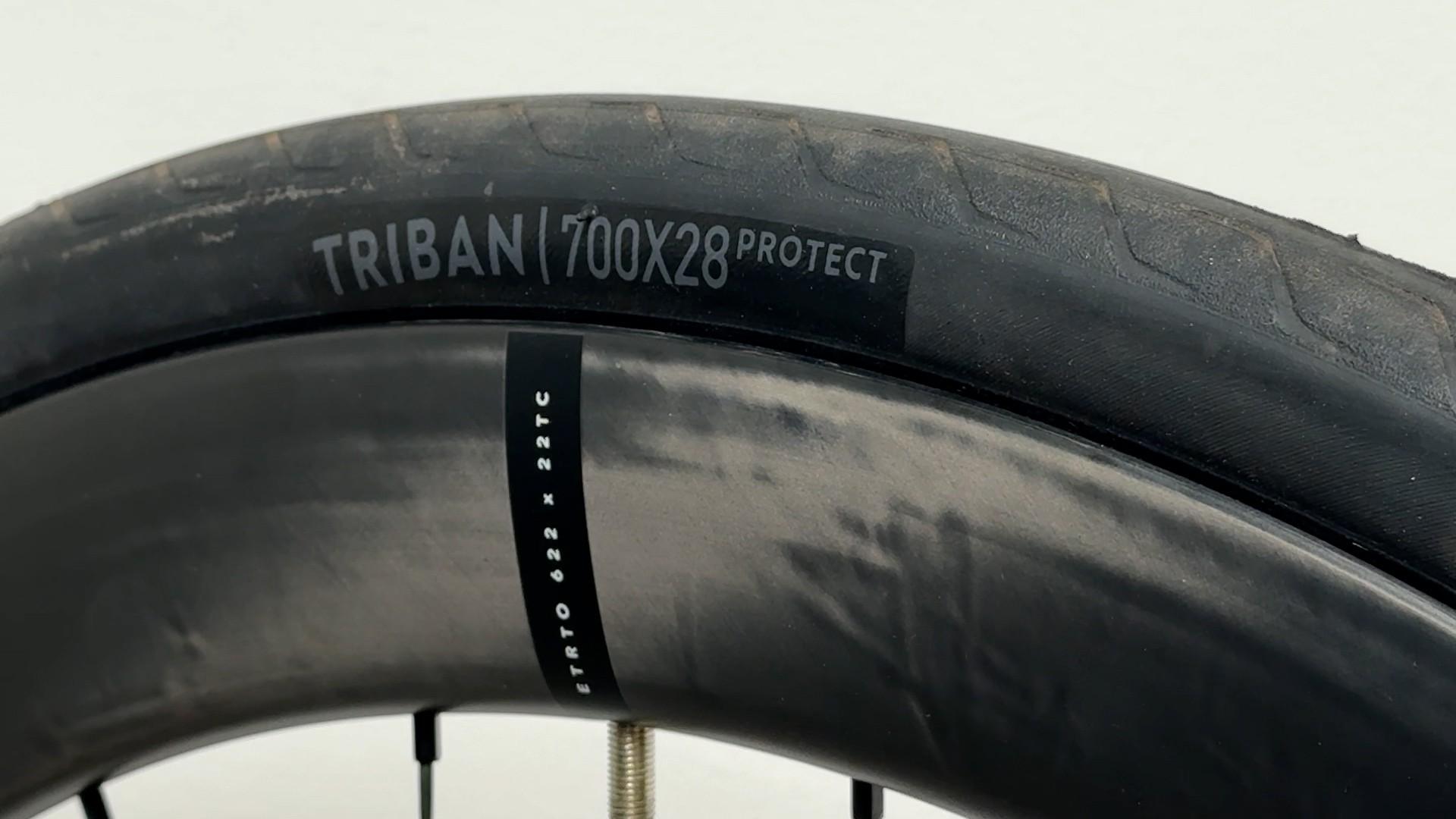Close-up of a Triban 700x28 road bicycle tire and inner tube with valve visible.