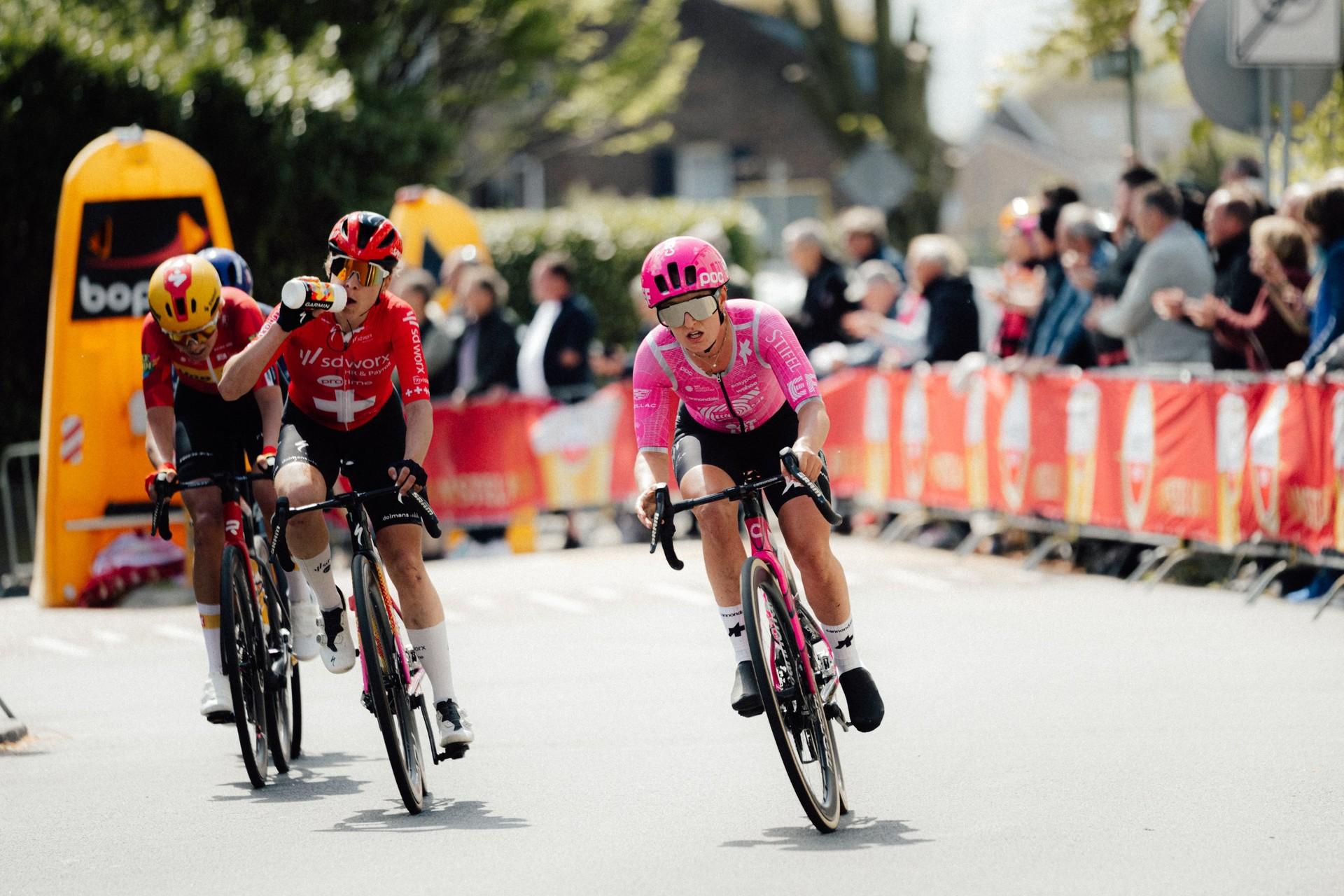 Cédrine Kerbaol rides a road bike on an indoor training track, wearing a pink helmet and jersey.