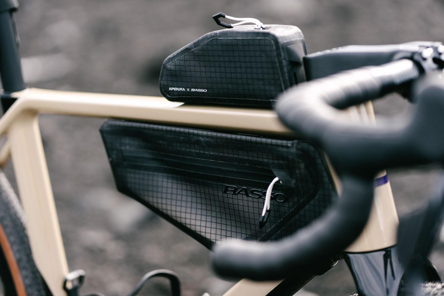 Apidura x Basso bikepacking bags mounted on a tan gravel bike frame.