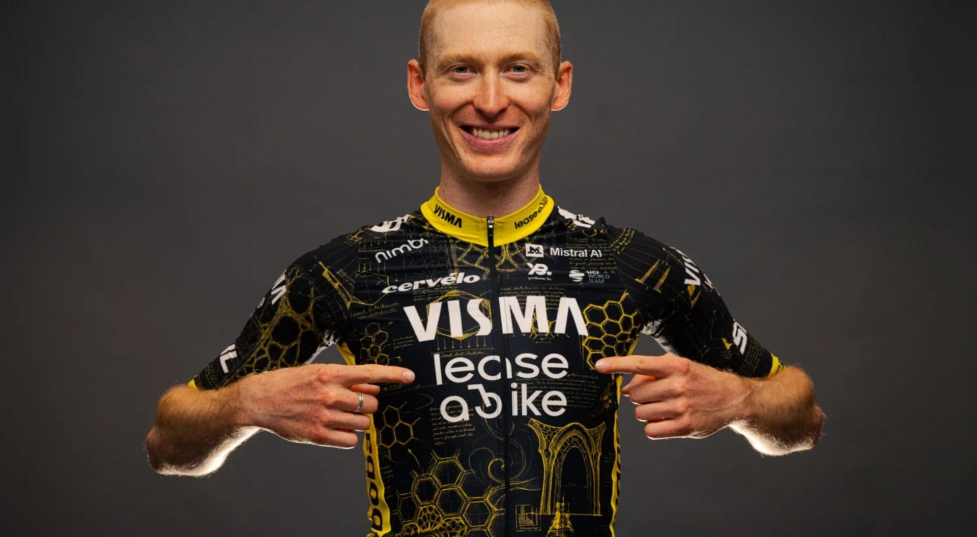 Cyclist in a Vismalecese jersey smiles and presents both hands in a victory gesture