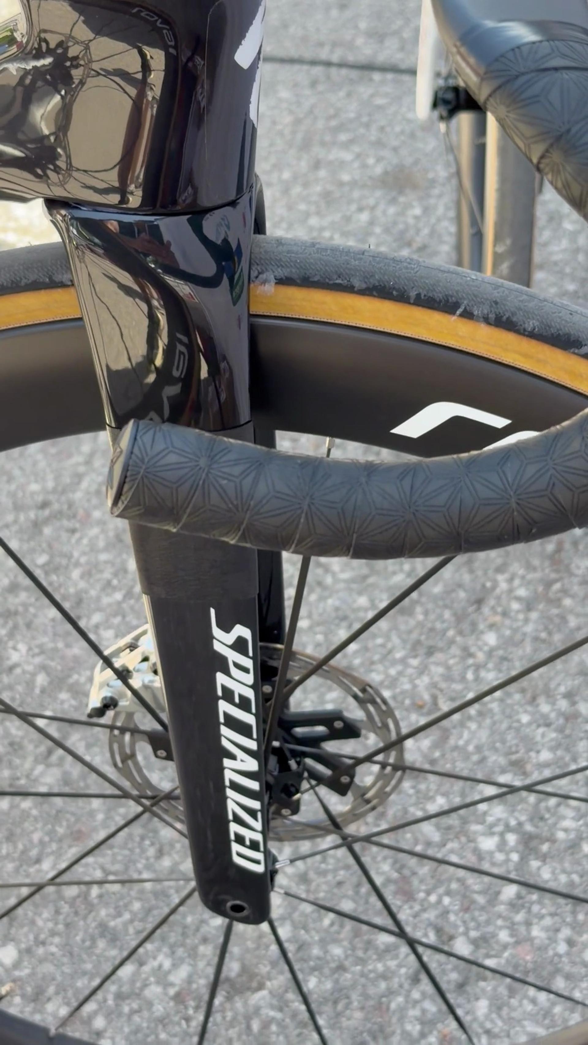 Close-up of a road bike’s front wheel and fork, showing the SPENCER graphic on the frame.