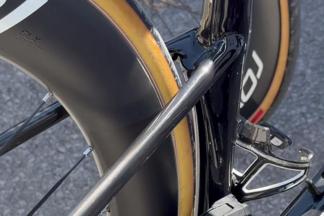 Close-up of a road bike’s front wheel and fork with sponsor branding near the handlebar area