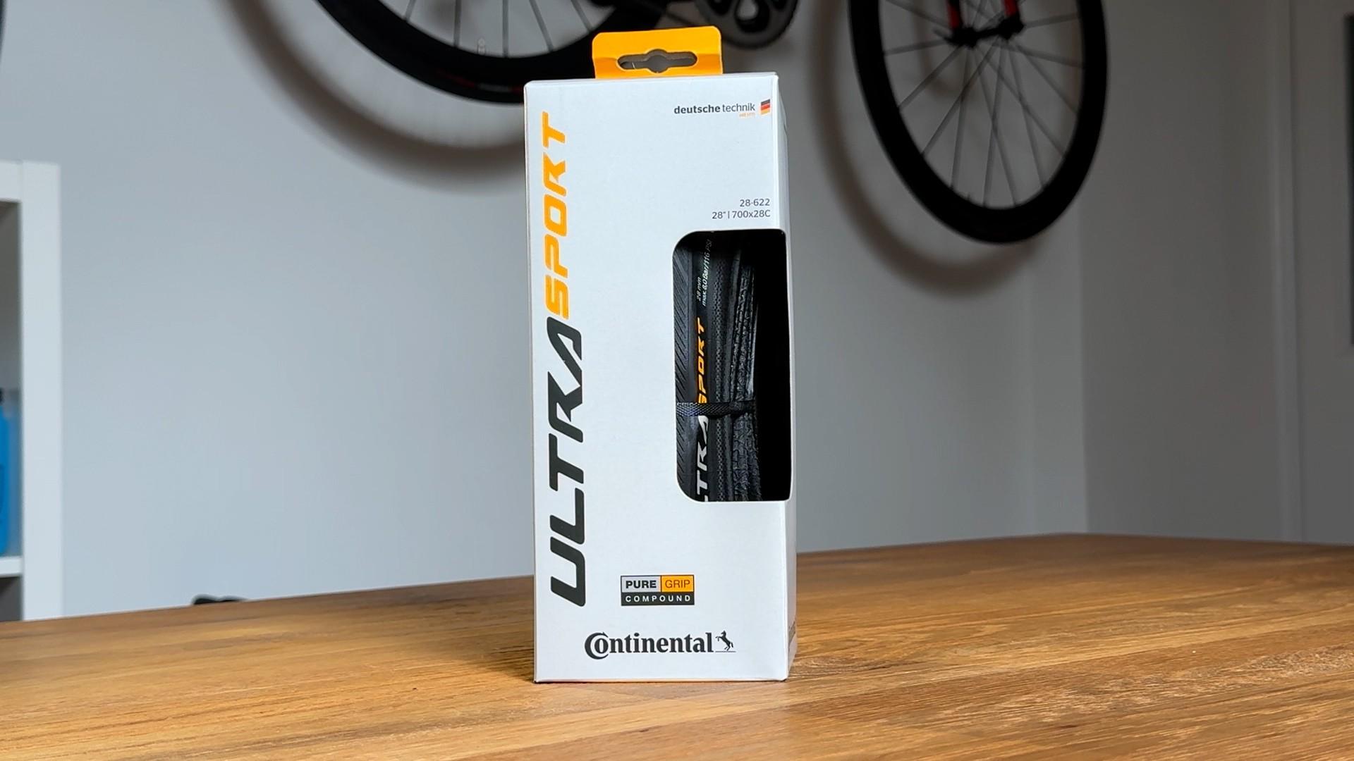 Continental Ultra Sport bicycle tire displayed in retail packaging on a wooden table