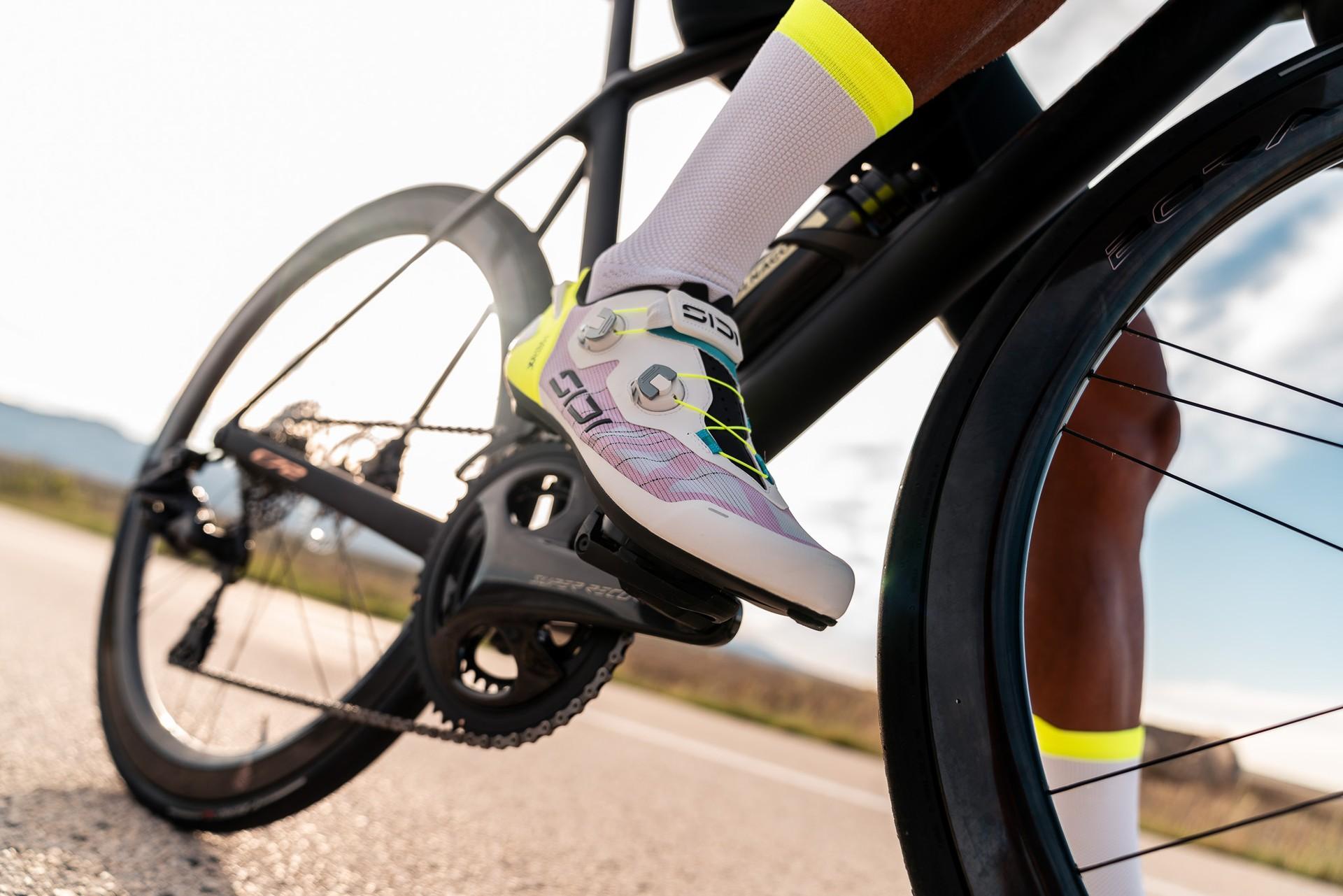 Cyclist’s rear wheel and drivetrain on a road ride, bike fitted with neon yellow and white socks