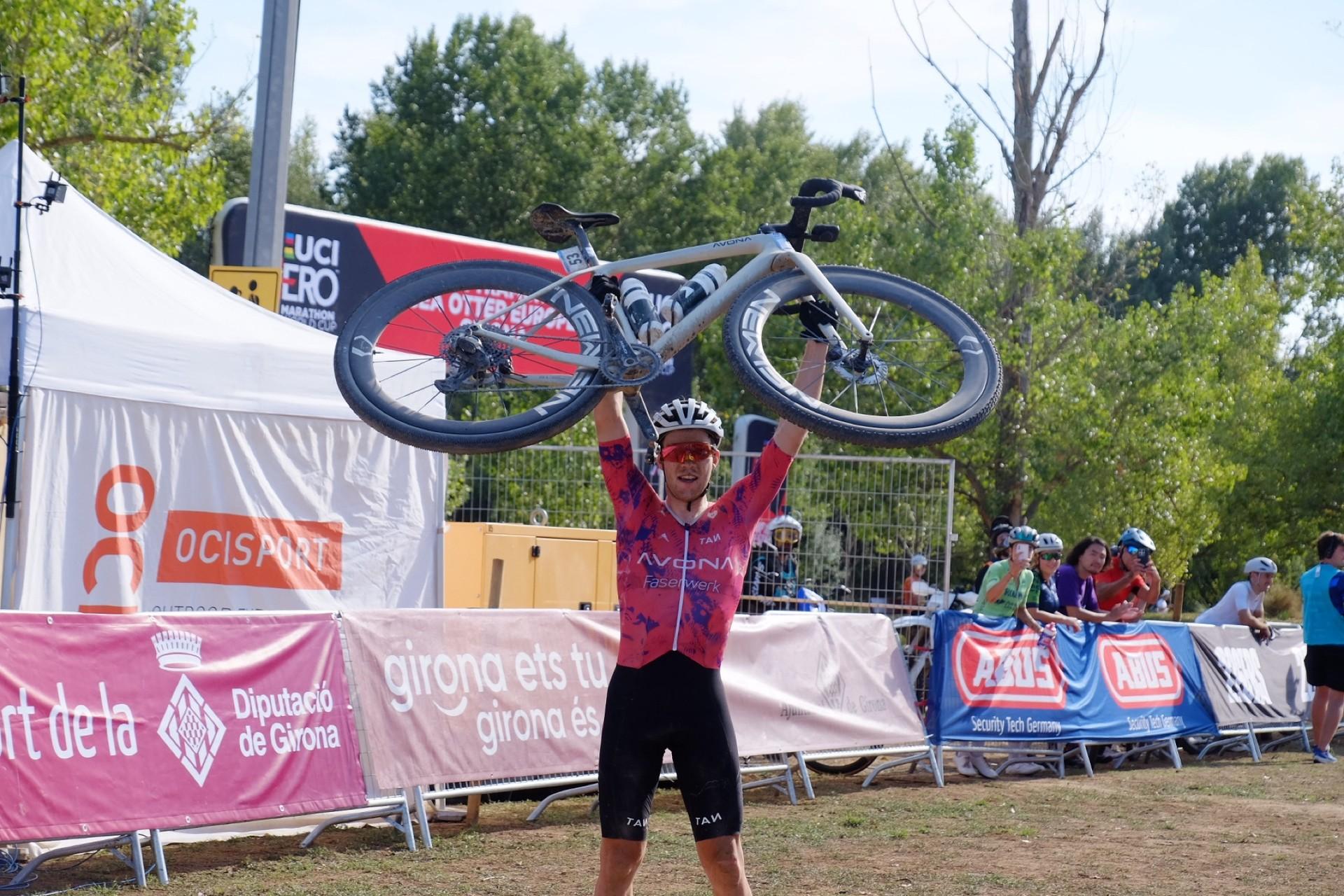 Leon Kaiser rides a 32-inch gravel bike during the Sea Otter Europe Girona race, with event barriers behind him.