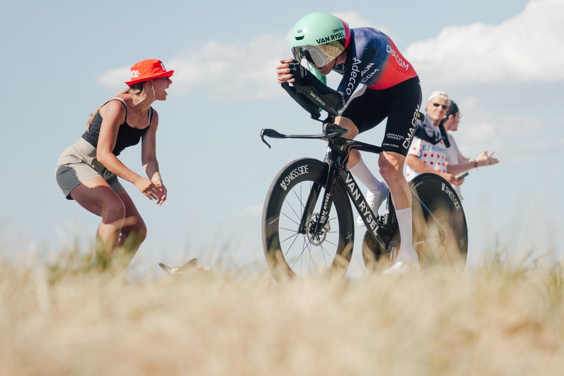 Cyclist Paul Seixas surges in an individual time trial at the Tour de France, kicking up dust as he rides.