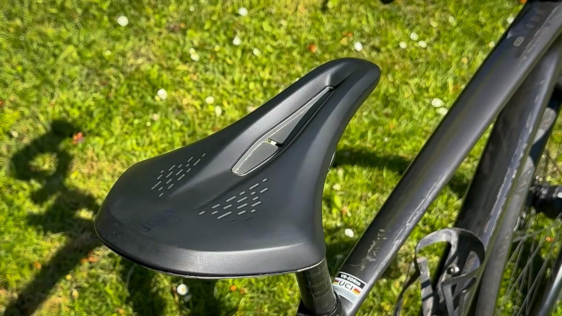 Close-up of a cyclist’s aerodynamic helmet and bike on green grass in sunlight
