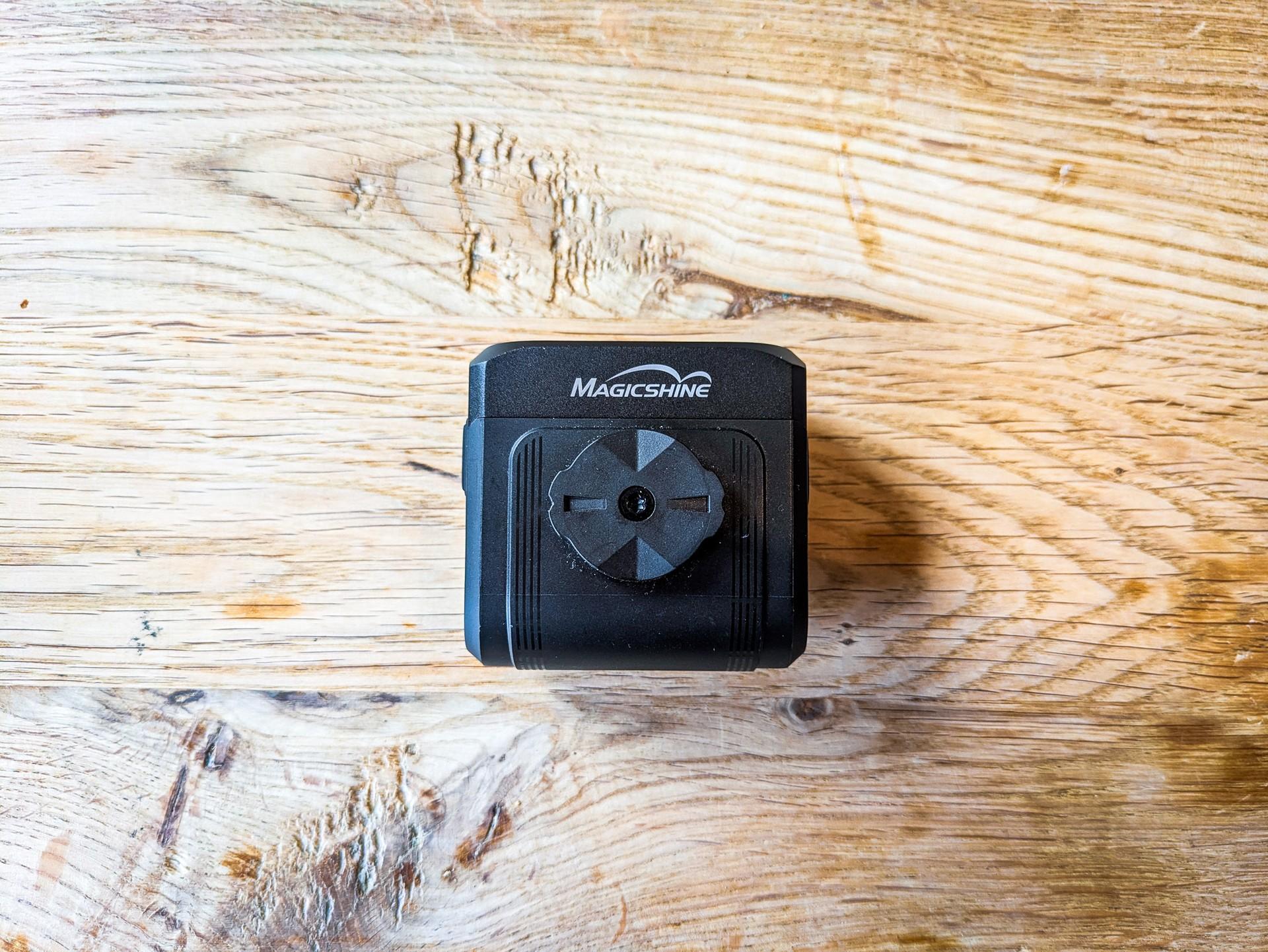 Magicshine HORI 1300 bike light showing its Garmin-style quarter-turn mount on a wooden table