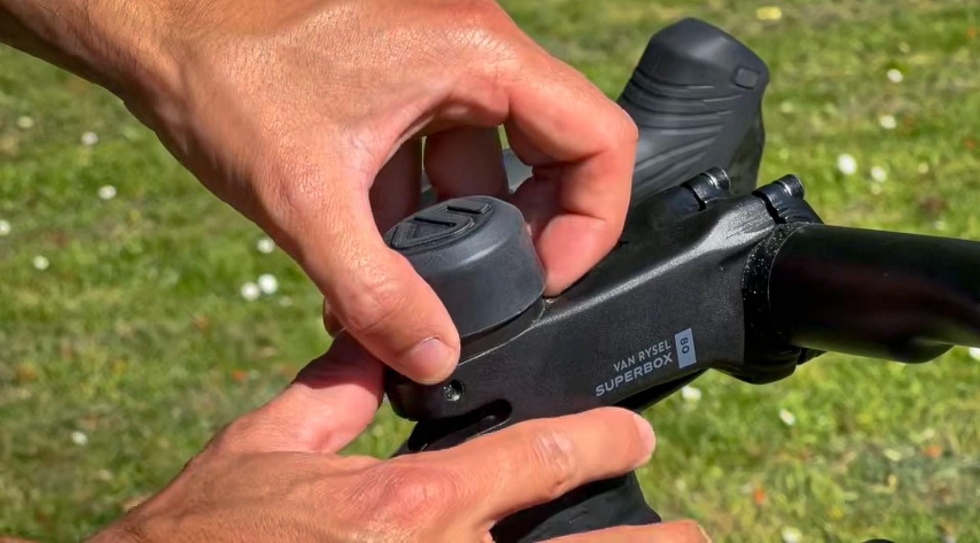 Hands adjusting a black Super/Boost bicycle handlebar shifter and control on an outdoor grass setting