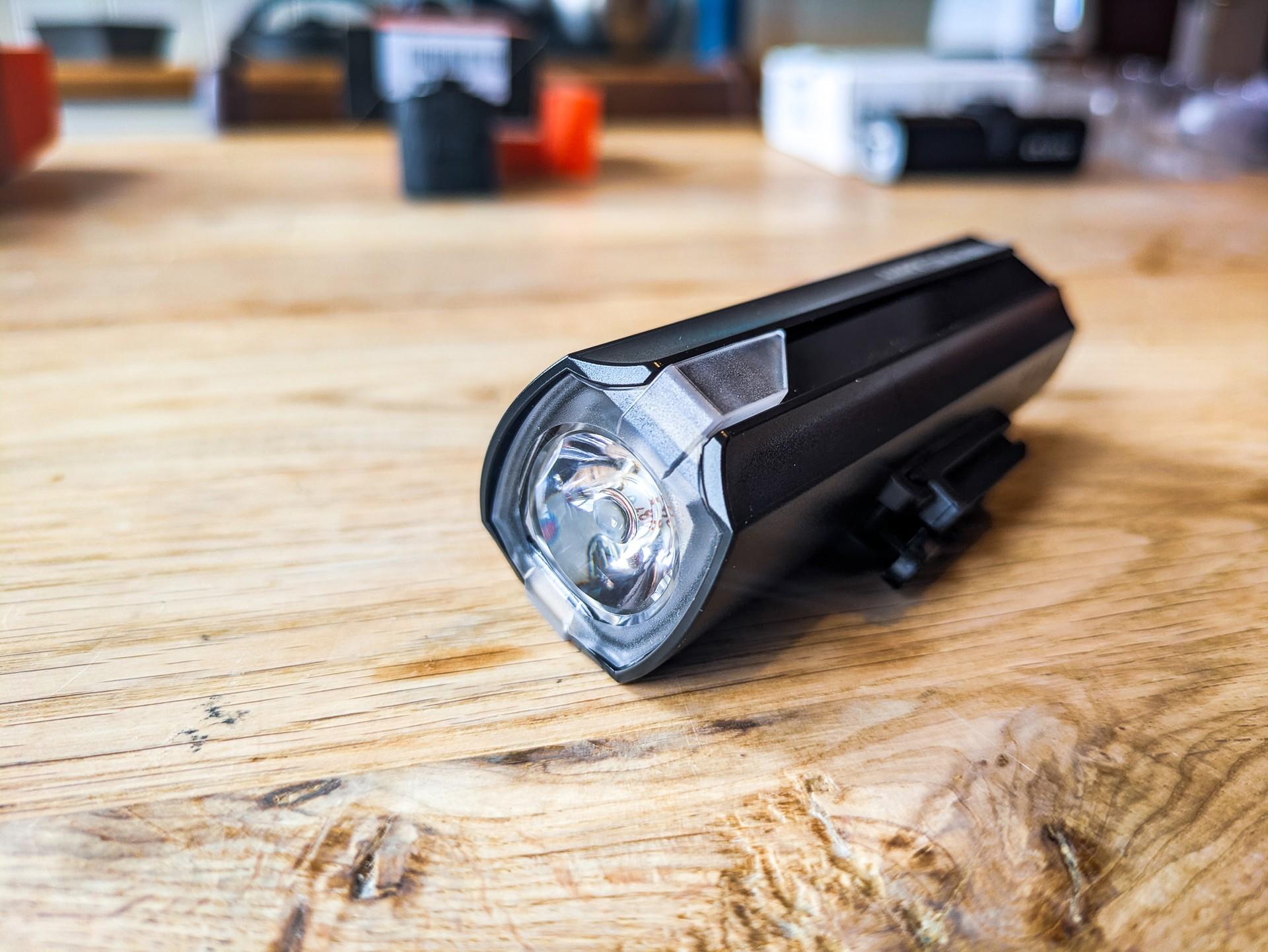 CatEye AMPP 500S front bike light resting on a wooden table, with its lens facing the camera