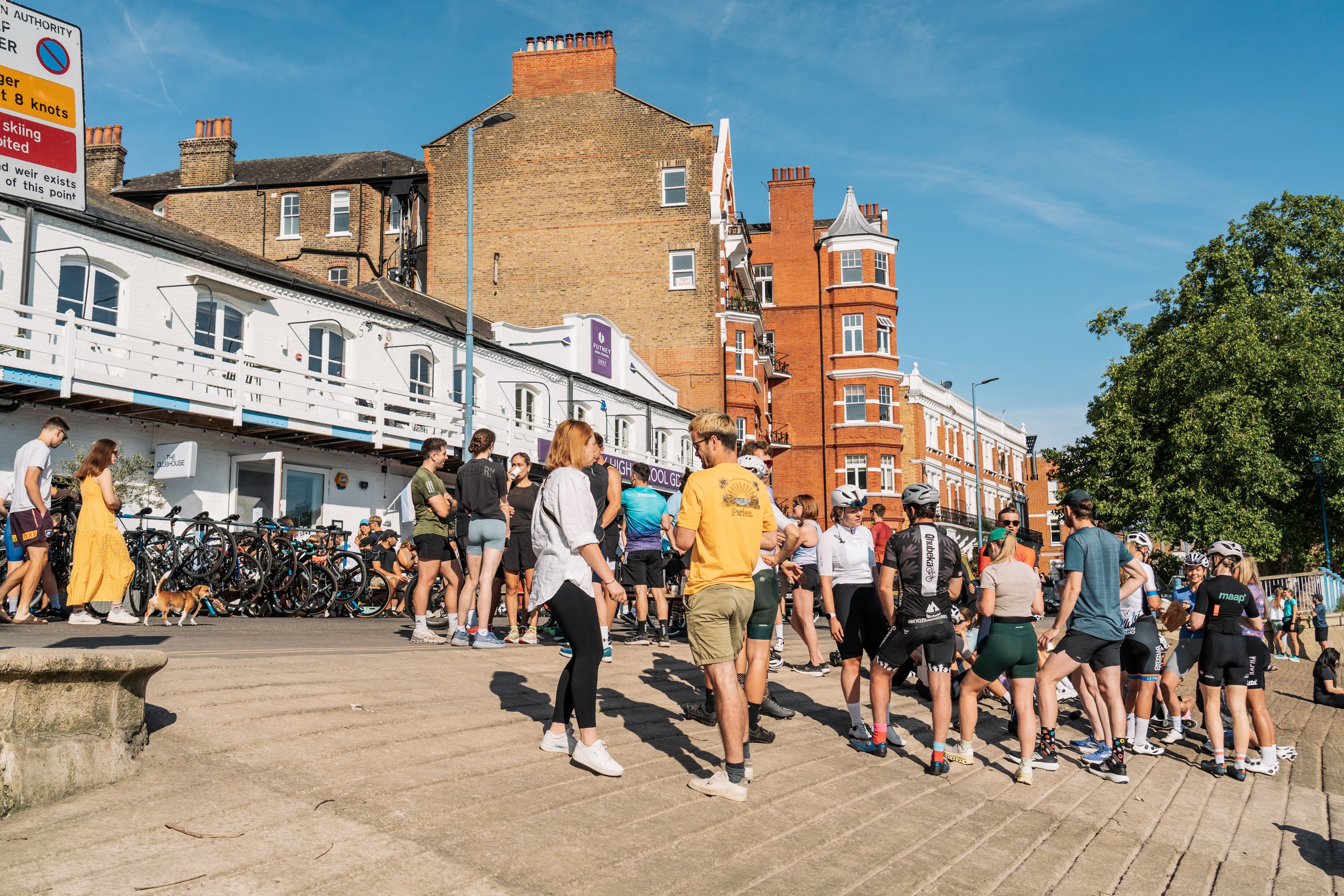 Cyclists and runners spread out on the riverbank in front of The ClubHouse cafe in Putney