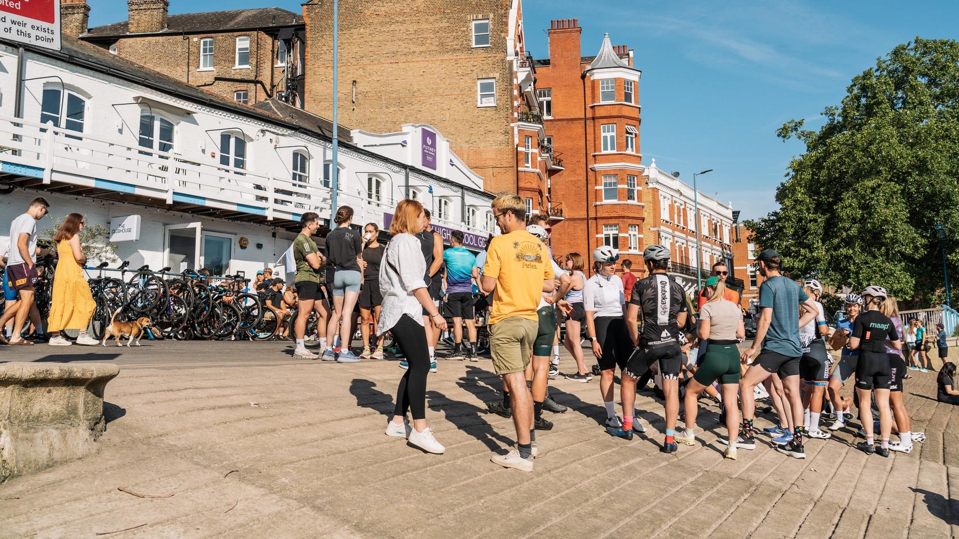Cyclists and runners spread out on the riverbank in front of The ClubHouse cafe in Putney