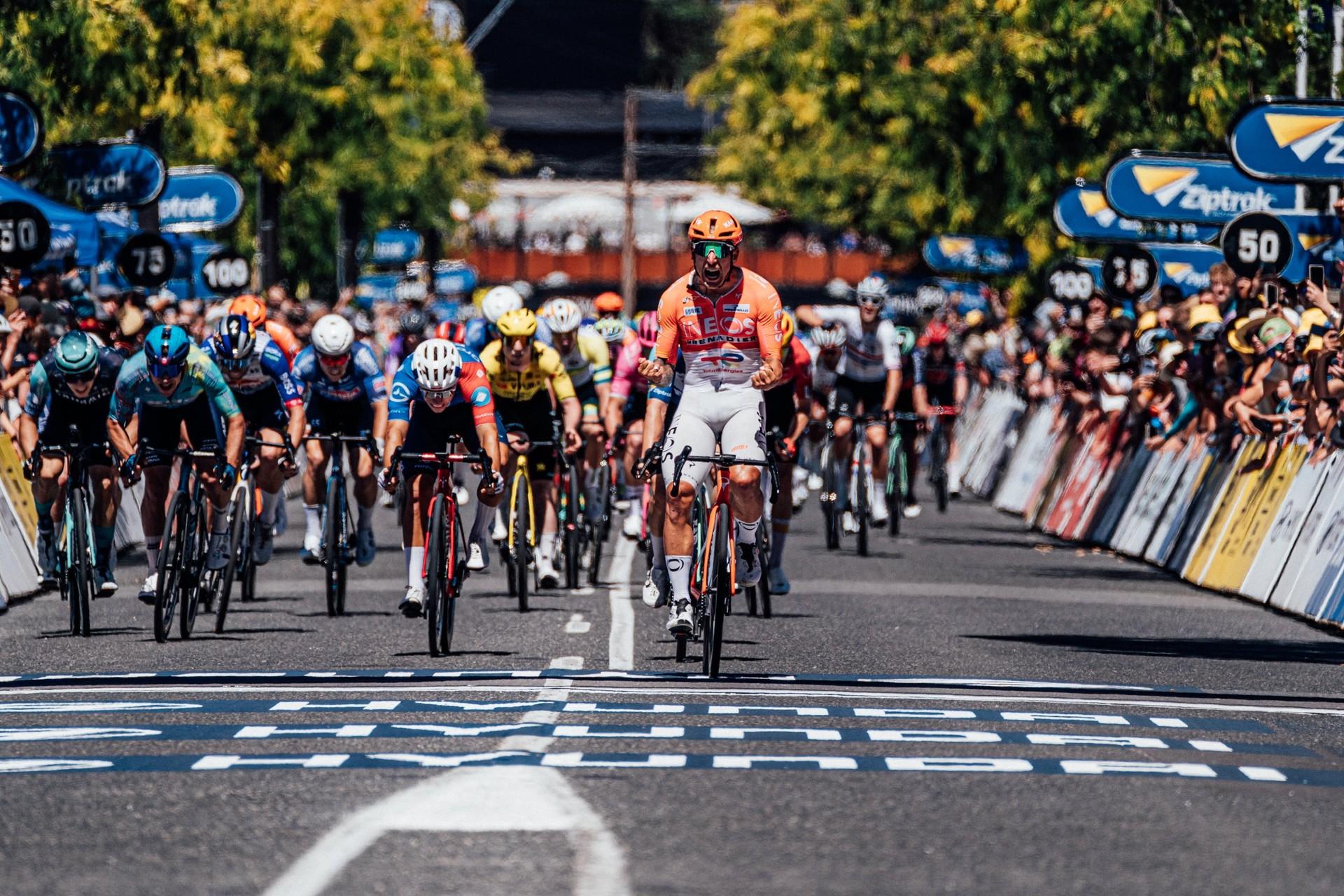 Sam Welsford leads a group of cyclists across a city street during a road race.