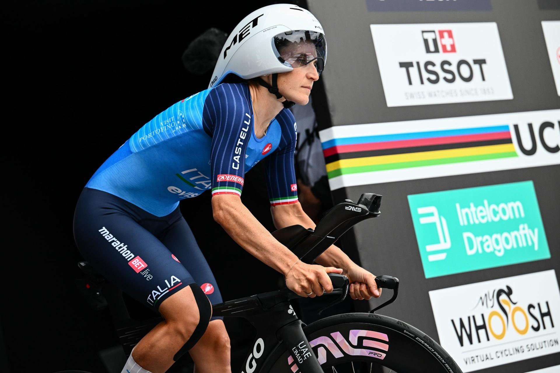 Elisa Longo Borghini rides her time trial bike past rainbow-striped UCI World Championships signage.