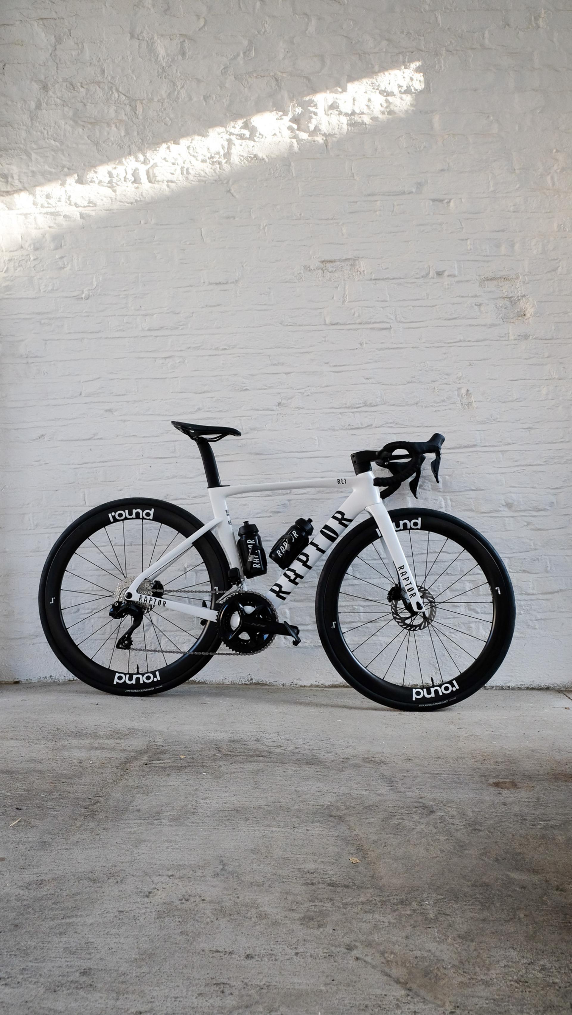 A Raptor road bike sat against a white wall