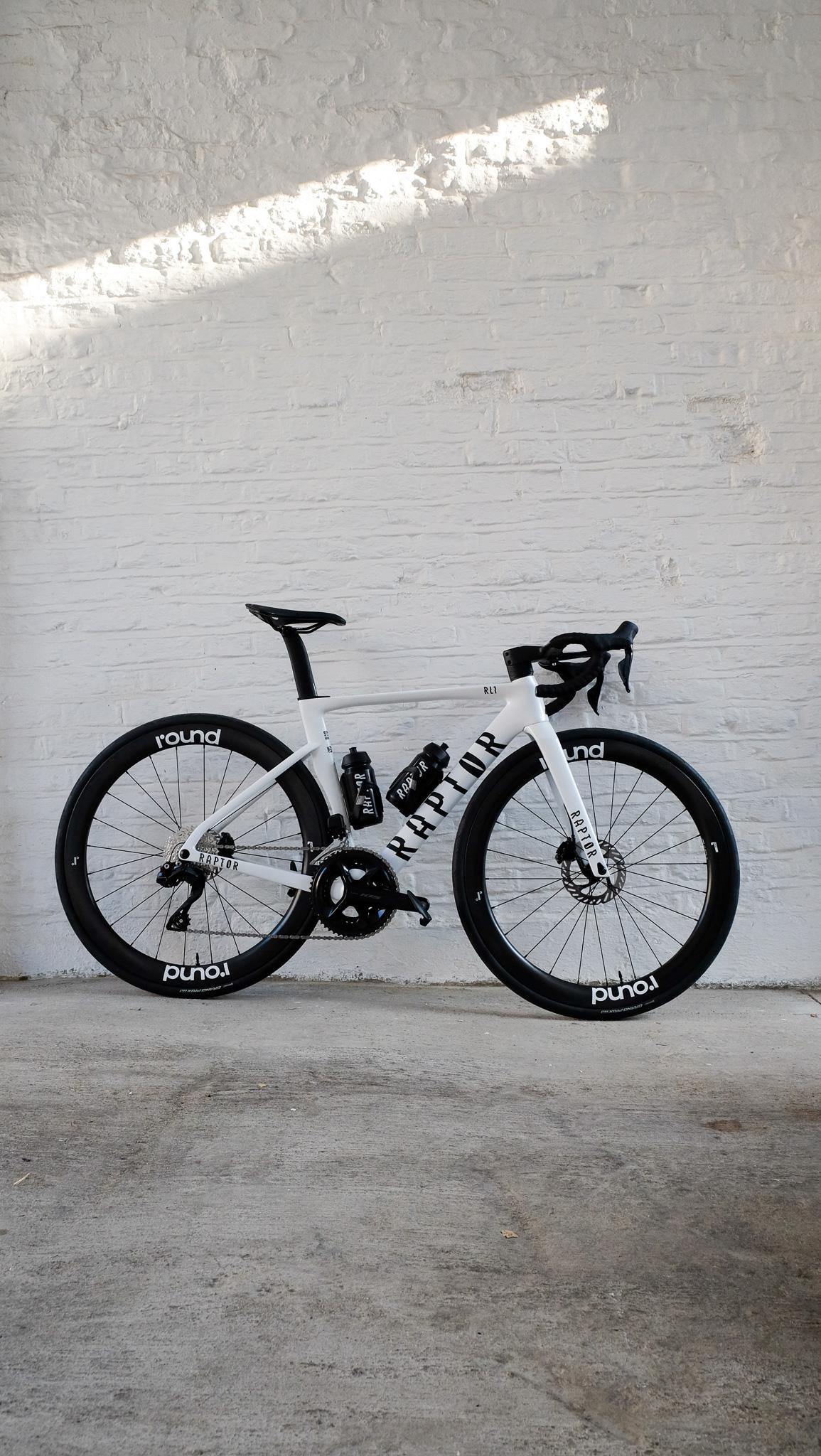 A Raptor road bike sat against a white wall