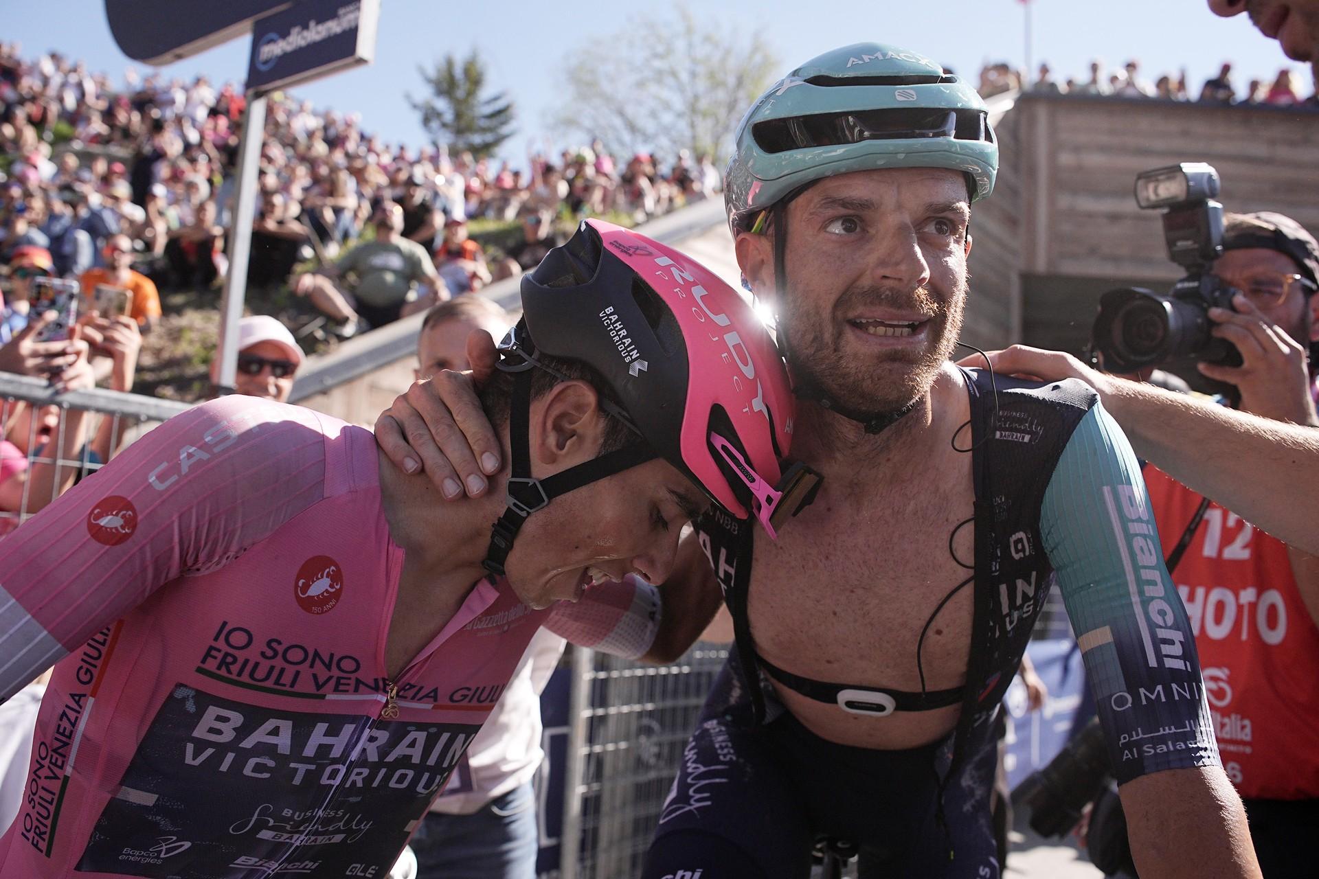 Cyclists in pink helmets and jerseys celebrate with fans along a road at a race finish