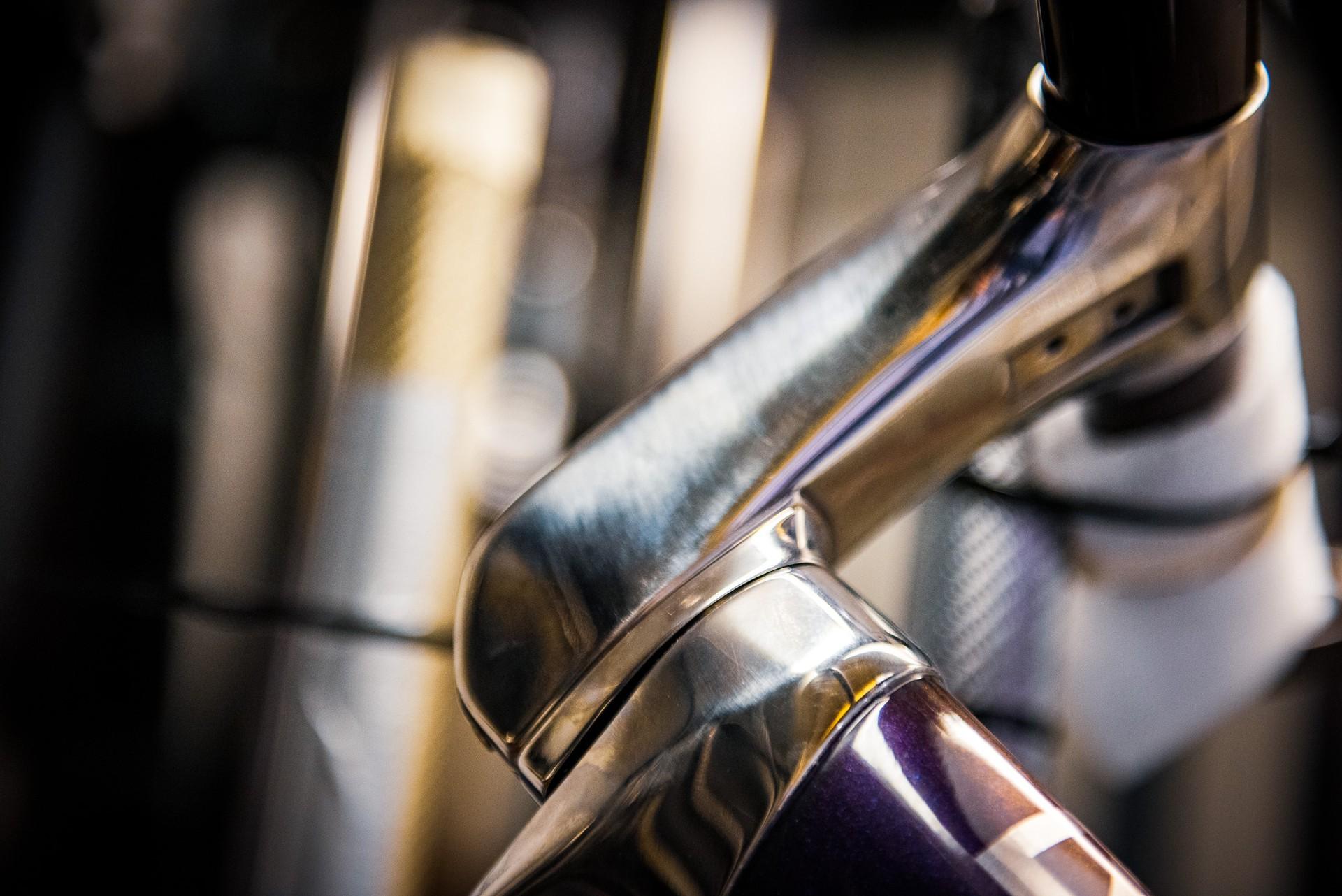 Close-up of a road bicycle frame and fork with glossy metal finish in soft light