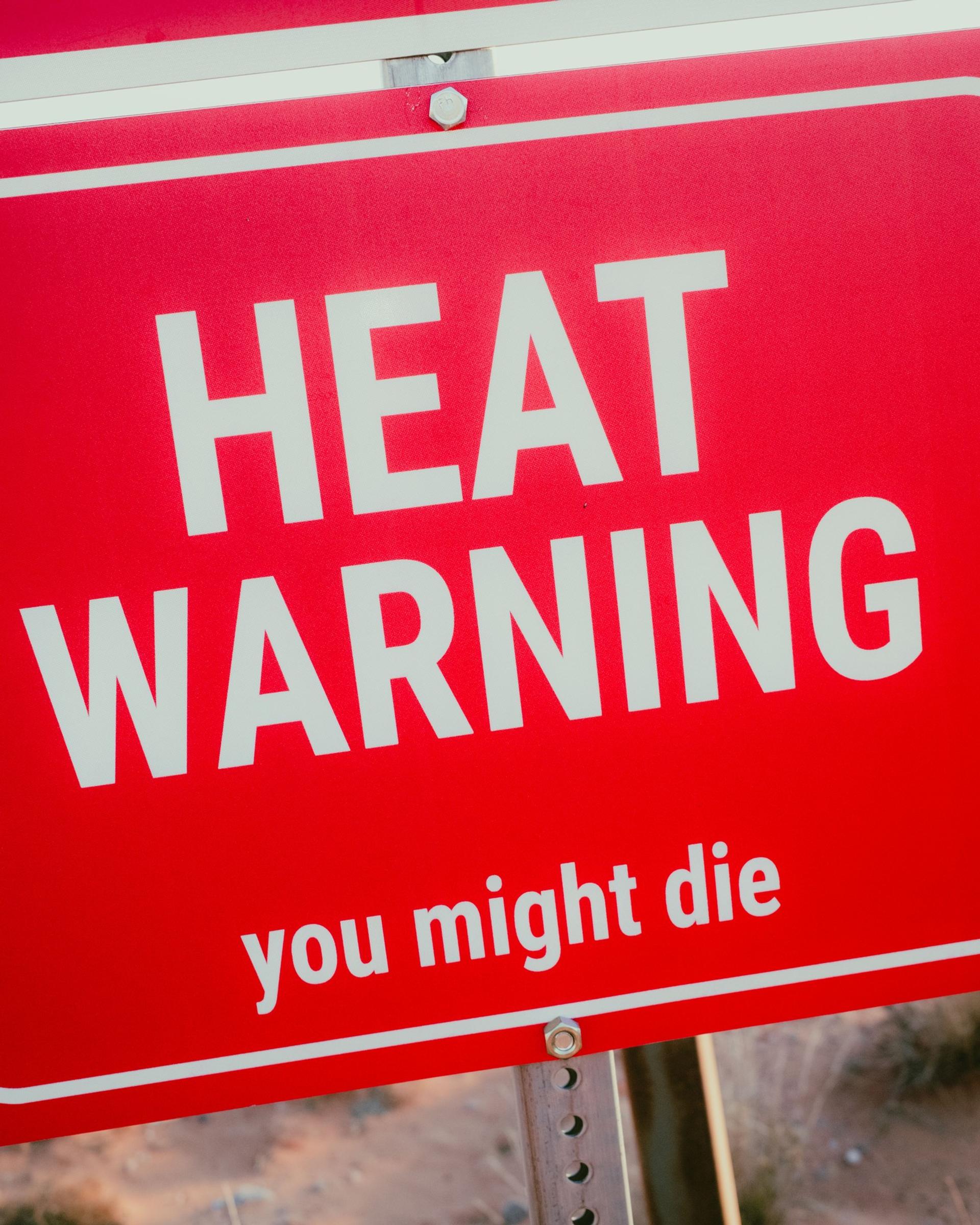 Red vehicle panel warning sign reading “HEAT WARNING: you might die.”