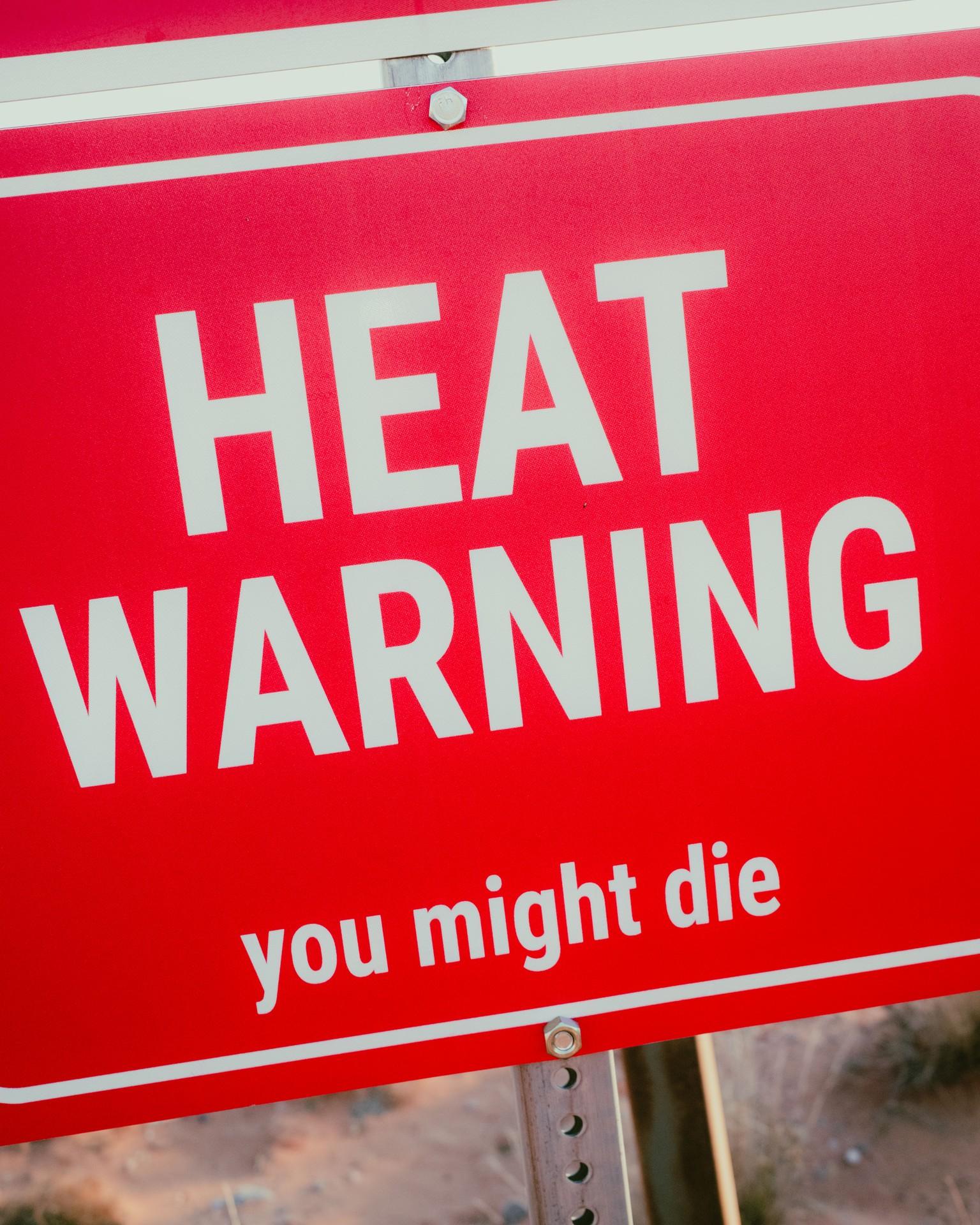 Red vehicle panel warning sign reading “HEAT WARNING: you might die.”