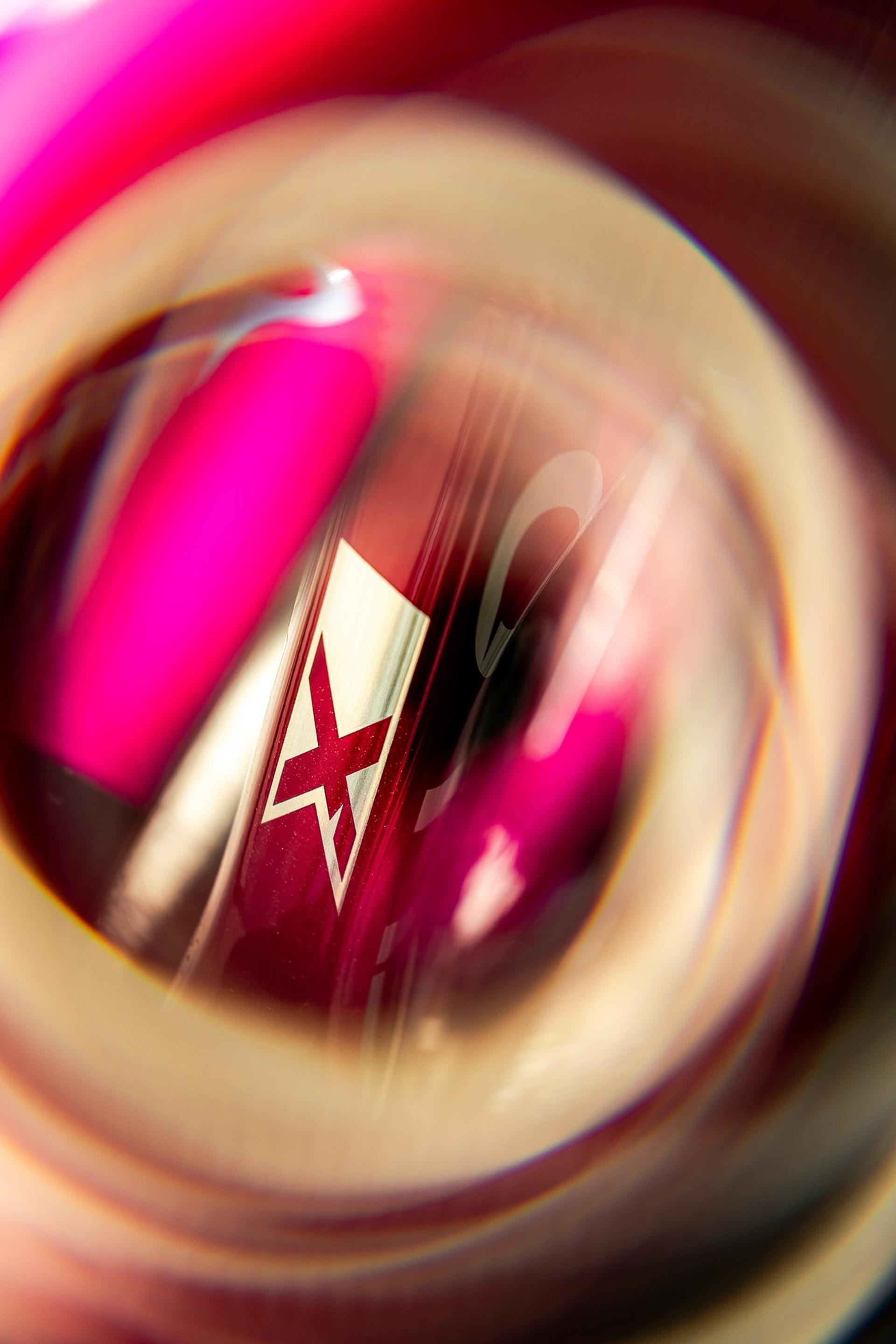 Close-up of a Pinarello logo on a red bicycle frame, viewed through a blurred wheel