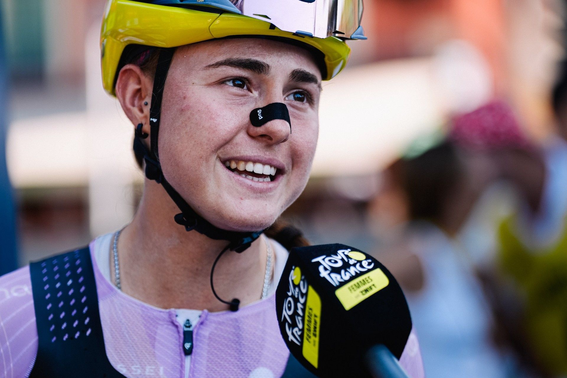 Paula Blasi smiles in a yellow helmet and race kit during the Tour de France Femmes.