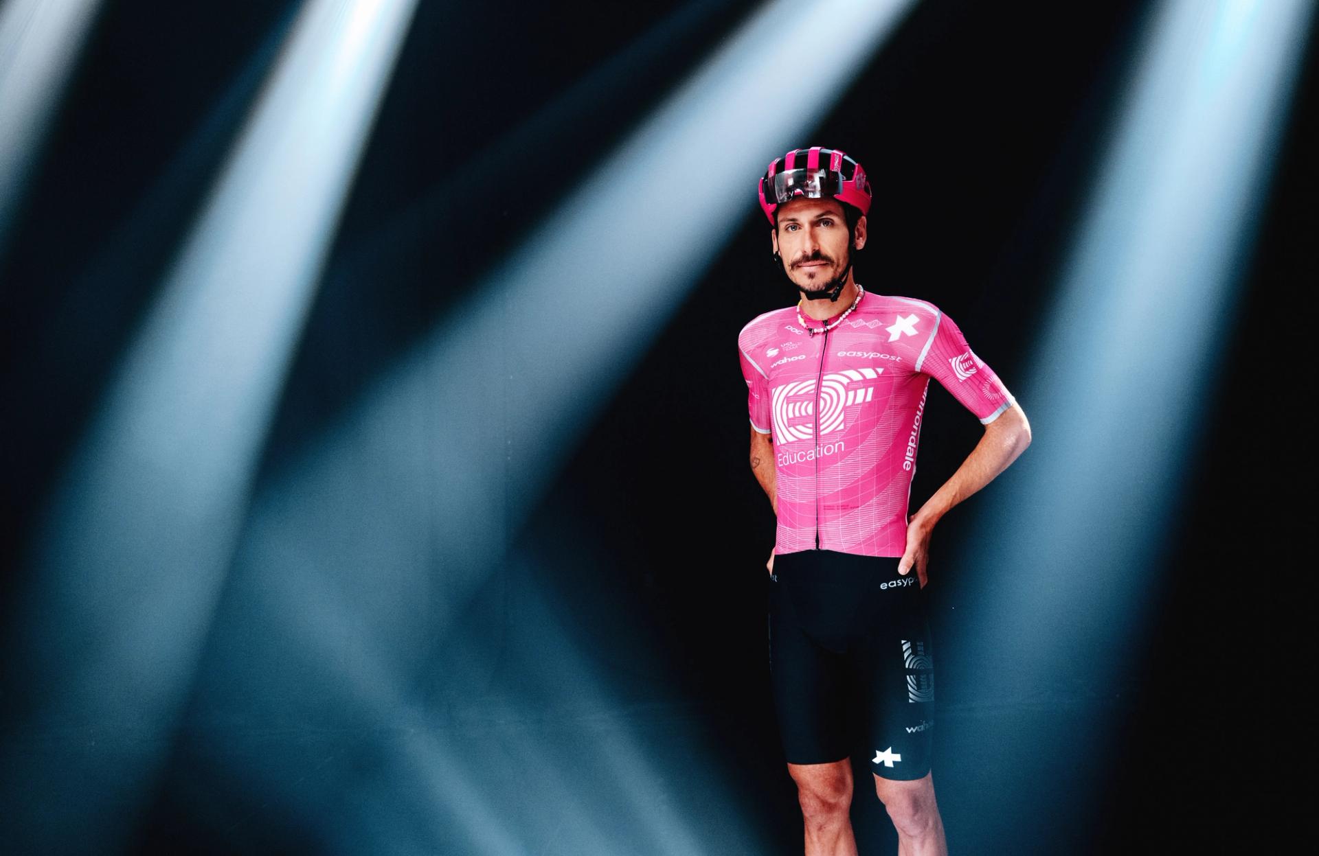 Lachlan Morton appears in the campaign wearing the team’s ASSOS kit, presented in a dramatic studio setup with spotlight lighting.