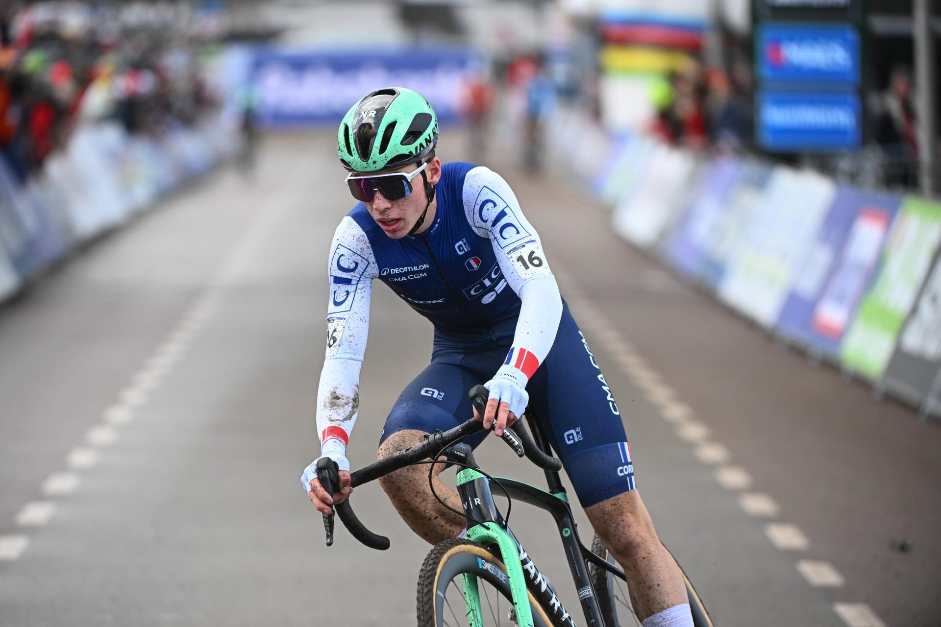 Aubin Sparfel rides toward the camera in a blue-and-white kit and teal helmet.
