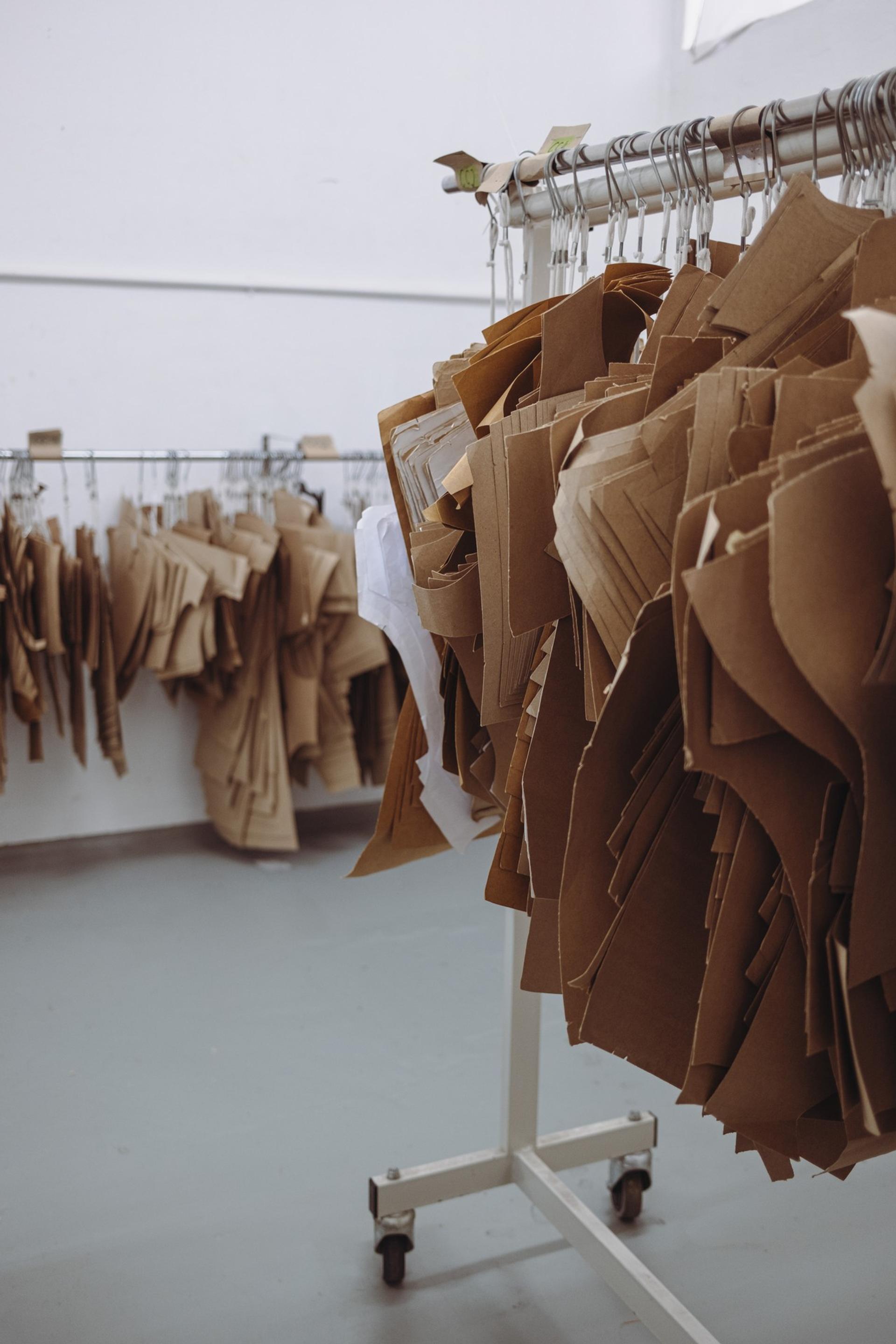 Rows of hanging kraft paper envelopes in an indoor display, secured on a metal rack