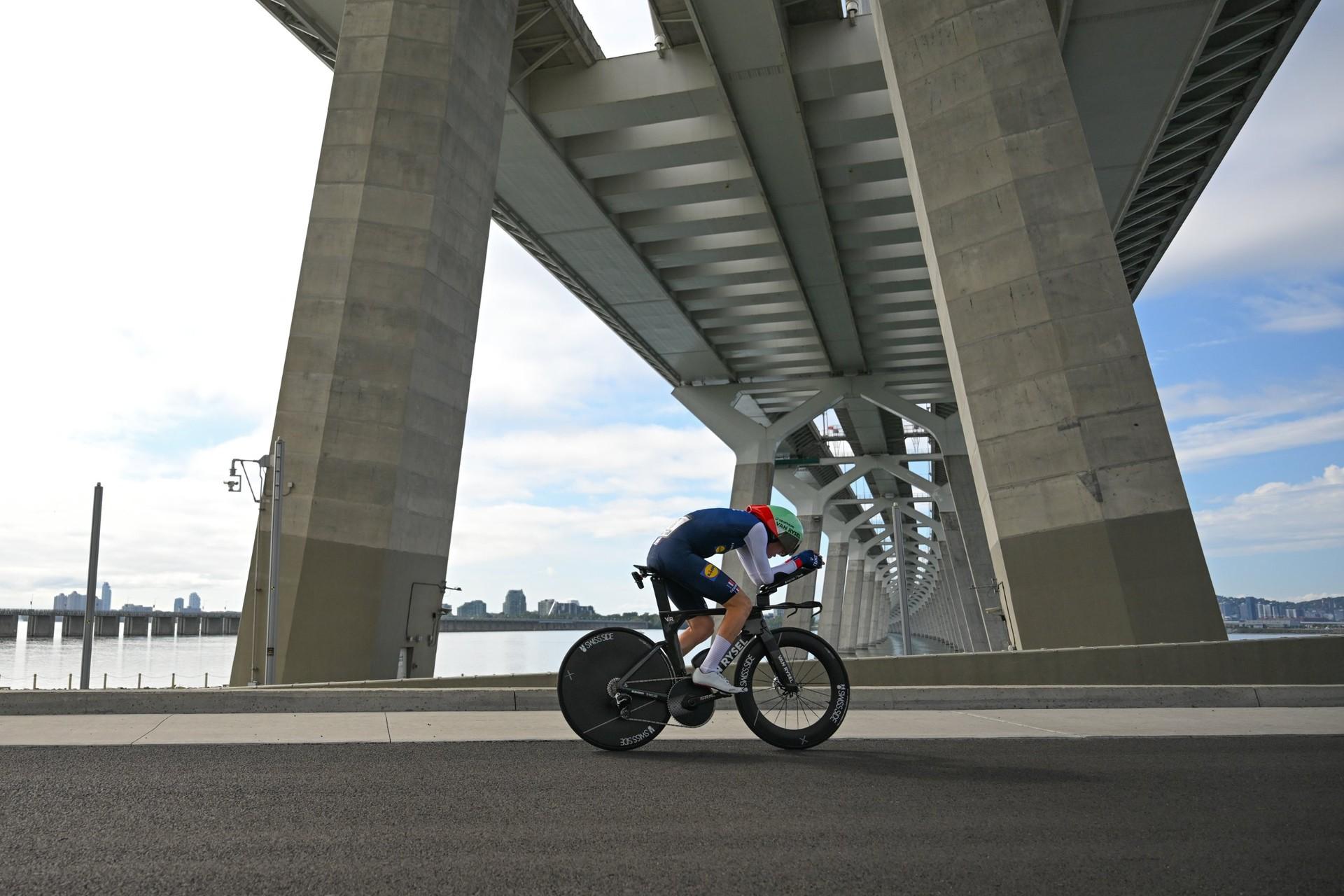 Paul Seixas rides his time trial bike beneath a large bridge during the elite Worlds time trial.