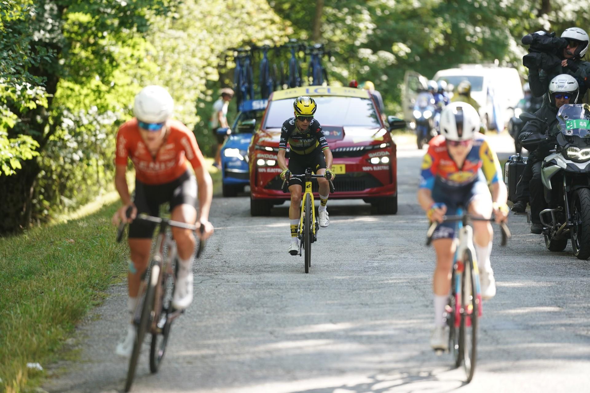 Women cyclists racing uphill in Tour de France Femmes with team car.