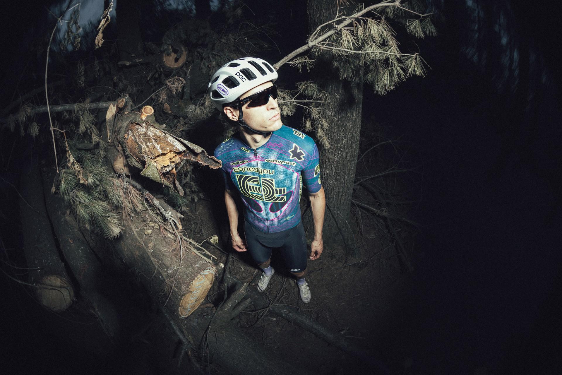 Cyclist in helmet and dark kit riding through a gritty tunnel, looking forward as spectators blur behind