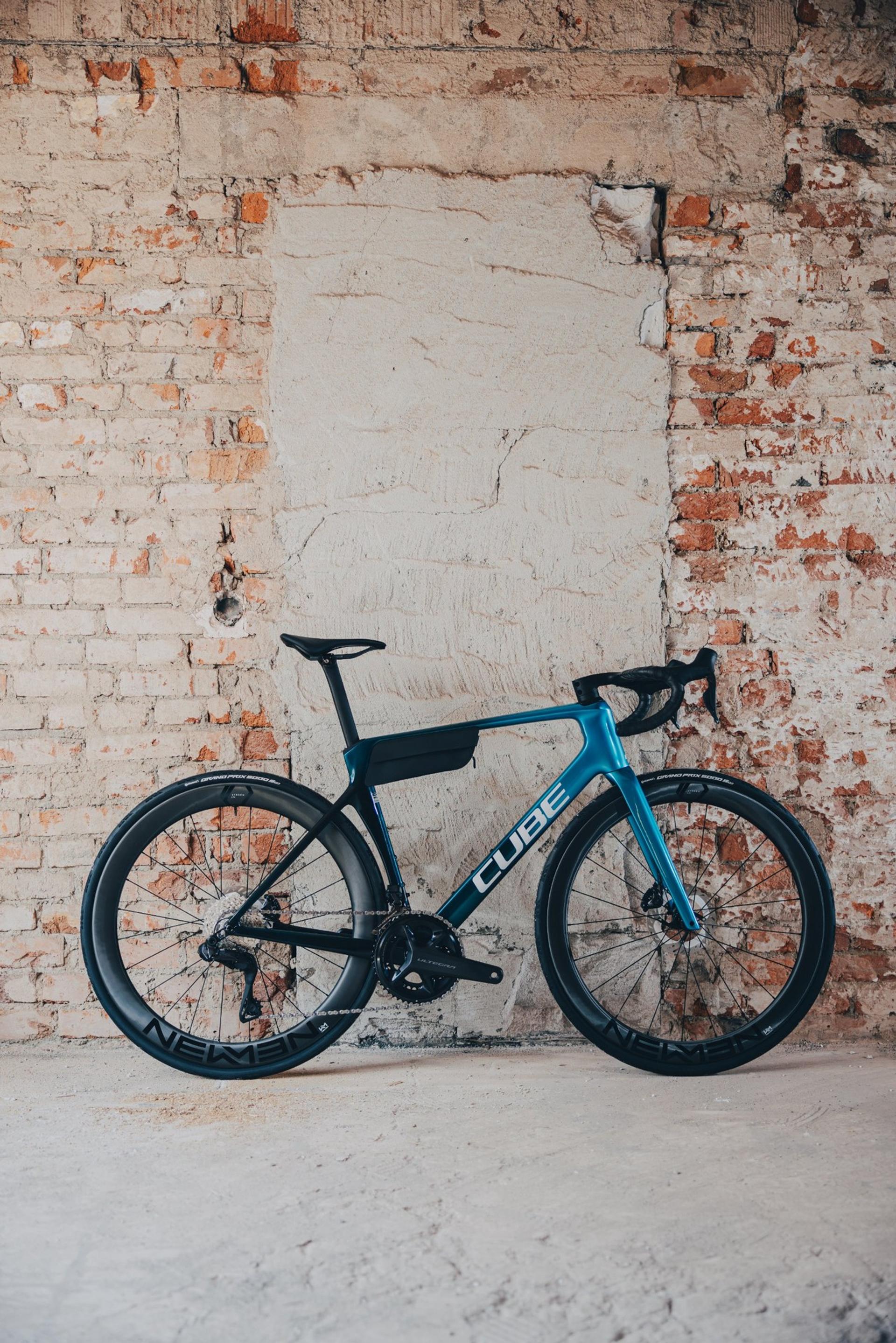 Blue and black Cube Agree road bike leaning against an exposed brick wall