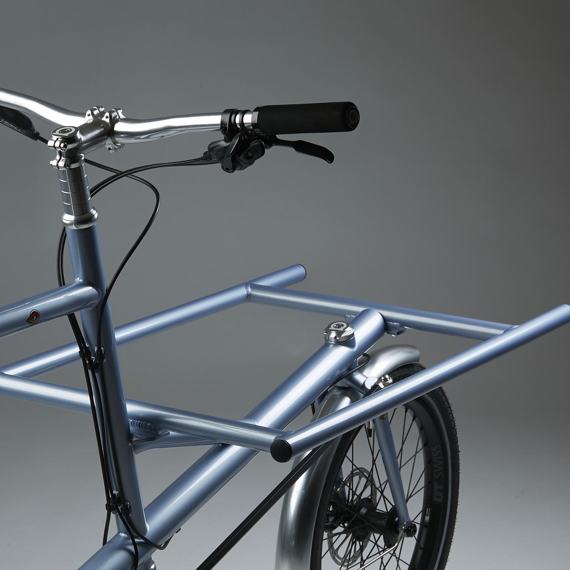 Close-up of a blue road bicycle handlebar and front wheel against a plain studio background