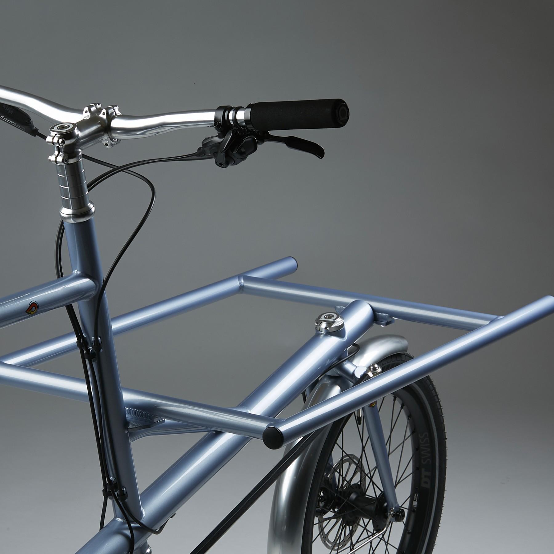 Close-up of a blue road bicycle handlebar and front wheel against a plain studio background
