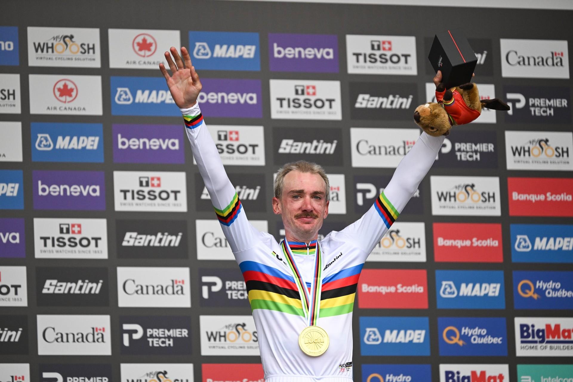 Brandon McNulty raises both arms in celebration, wearing his rainbow-banded world champion’s jersey.