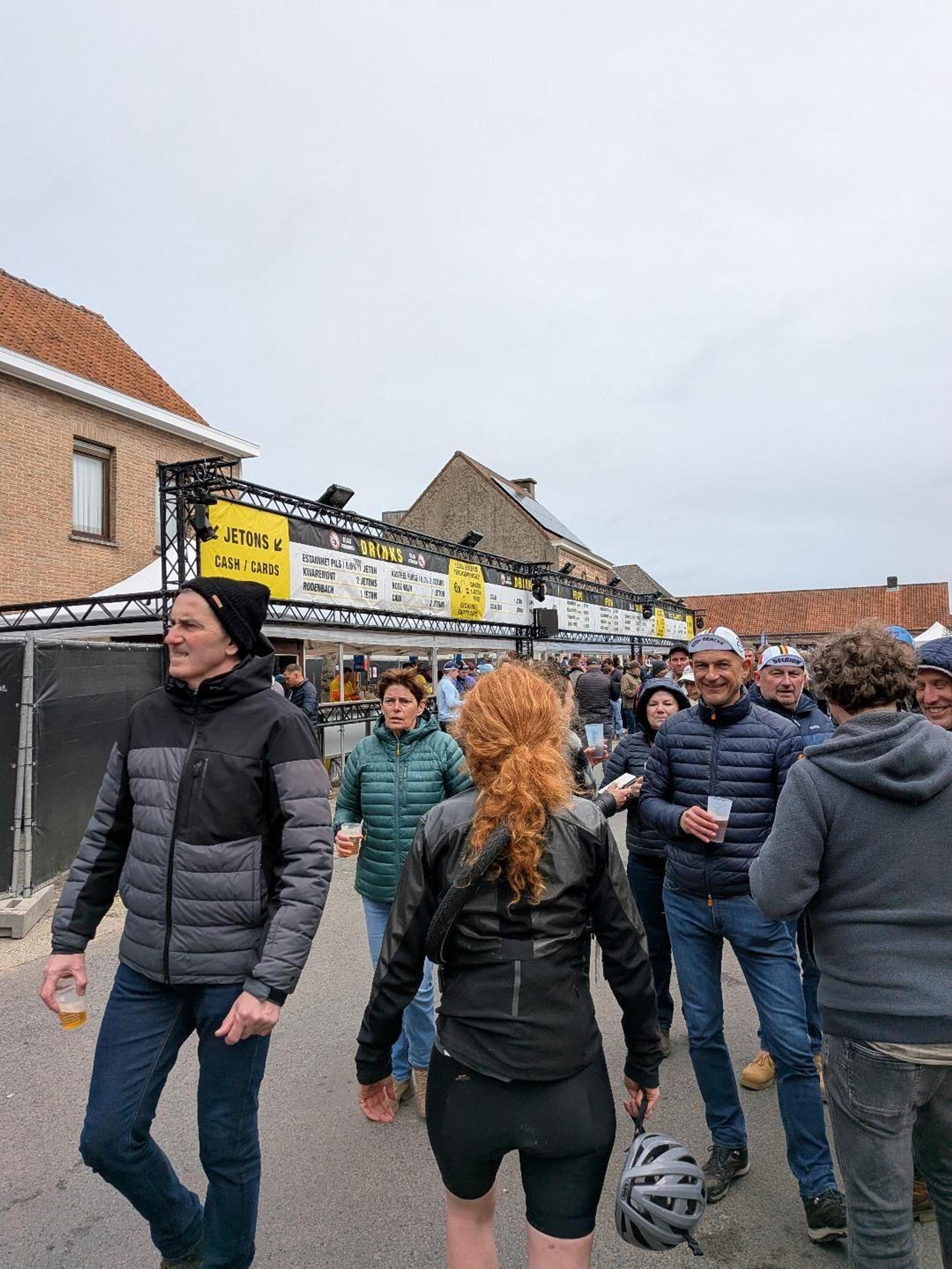 Crowds of fans walk between beer tents and drinks stands at the Oude Kwaremont fanzone during the 2026 Tour of Flanders