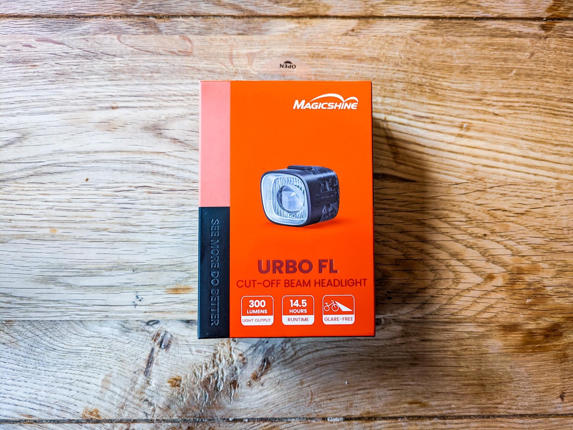 Magicshine URBO FL bike light box on a wooden table, showing the compact black front light