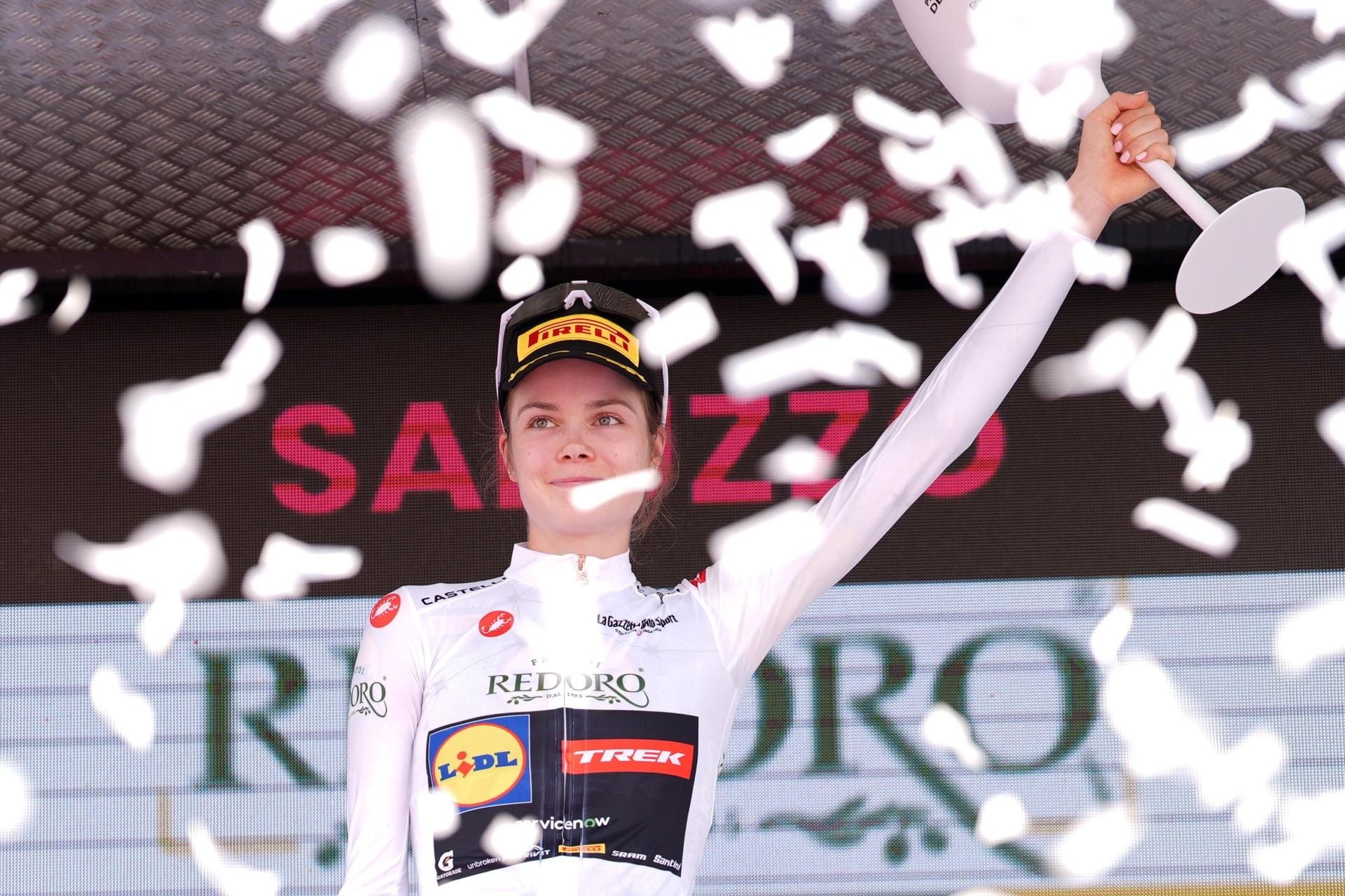 Cyclist in a Soudal team jersey raises an arm during a race, with snowflakes falling.