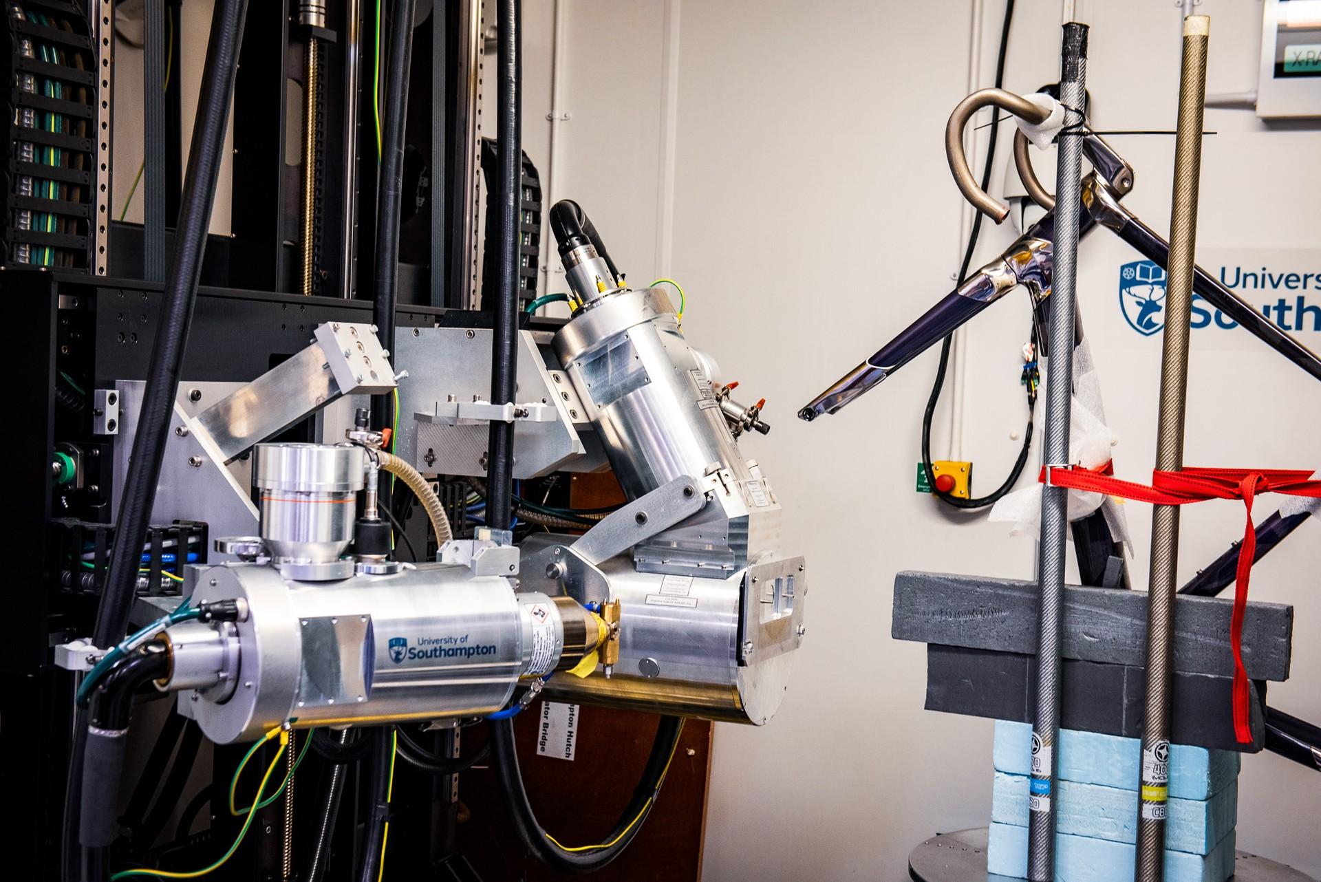 Laboratory bike-component test rig with mounted sensor hardware and cables in a white facility.