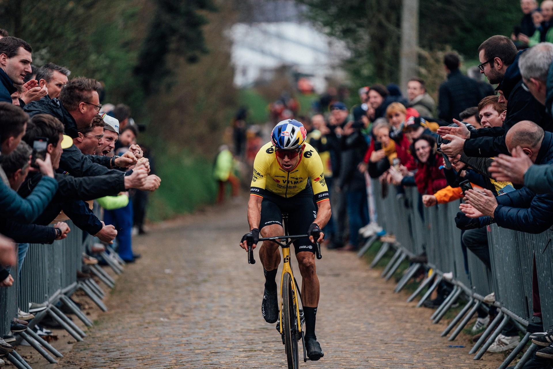 Wout van Aert climbing a steep cobblestone sector at the E3 Saxo Classic surrounded by cheering fans.
