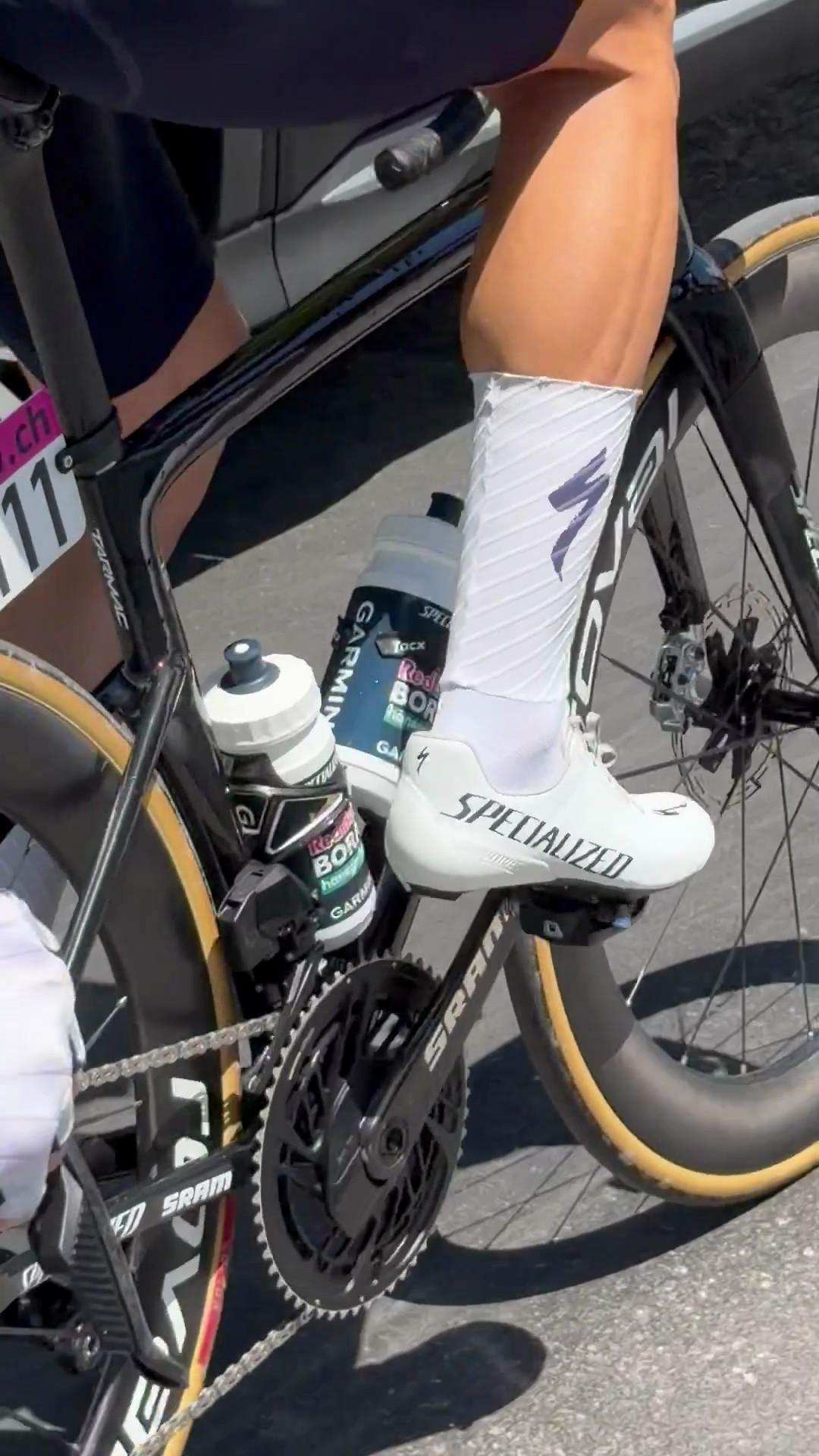 Road bike wheel and white cycling shoe clipped into the pedal during a race