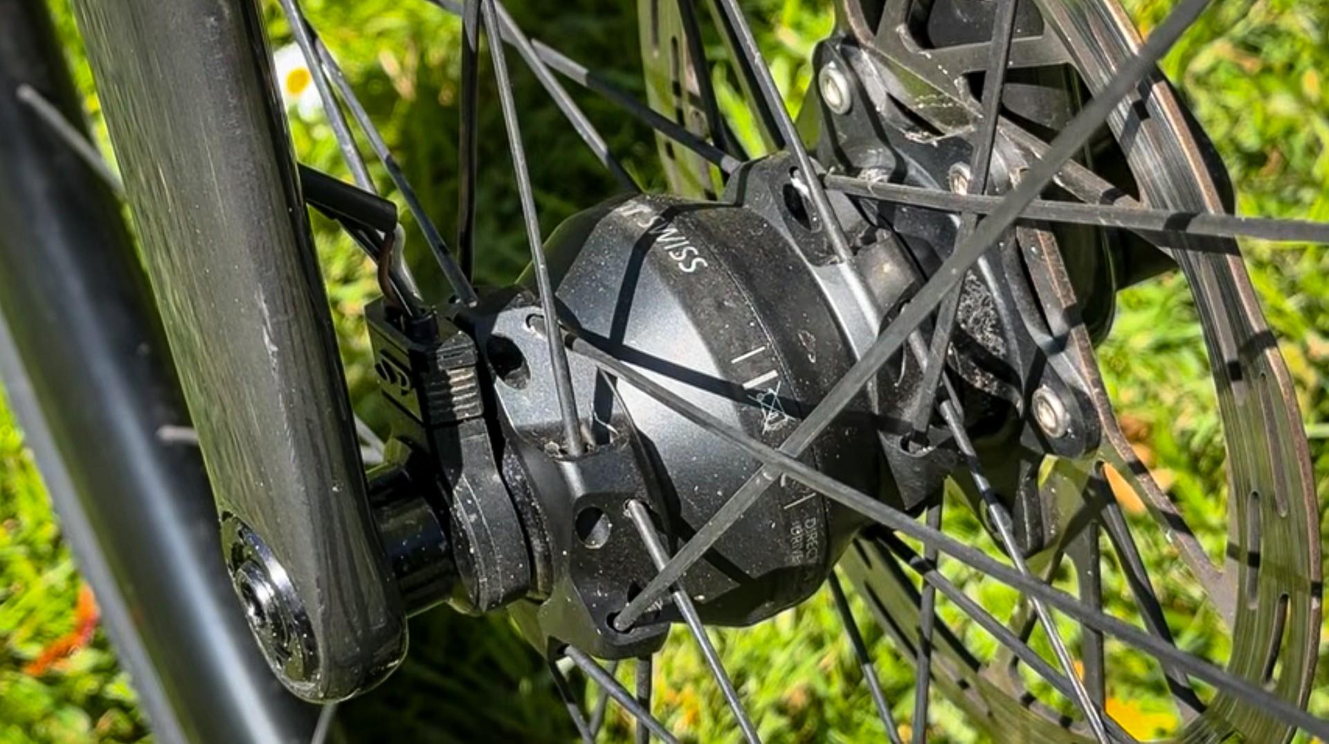 Close-up of a mountain bike front disc brake rotor and suspension fork in motion on a trail