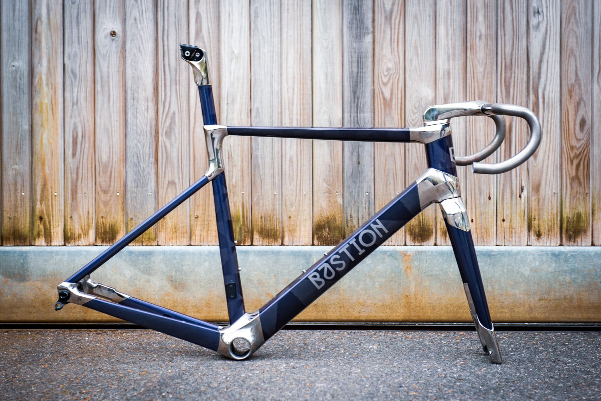 Close-up of a blue racing bicycle frame and handlebars leaning against a wooden fence