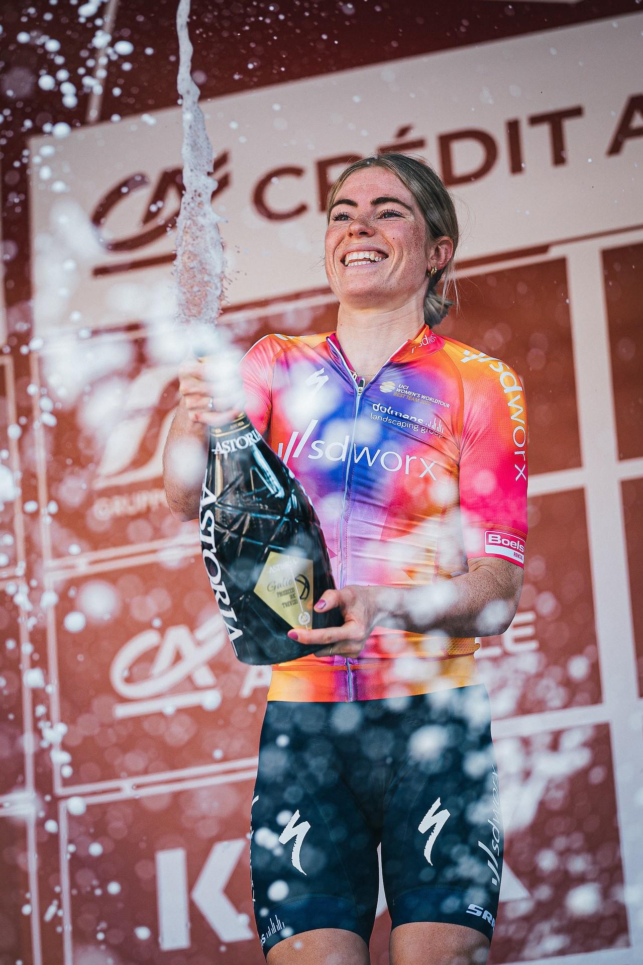 Demi Vollering of Team SD Worx celebrates her Strade Bianche Women's Race victory with a champagne spray on the podium.